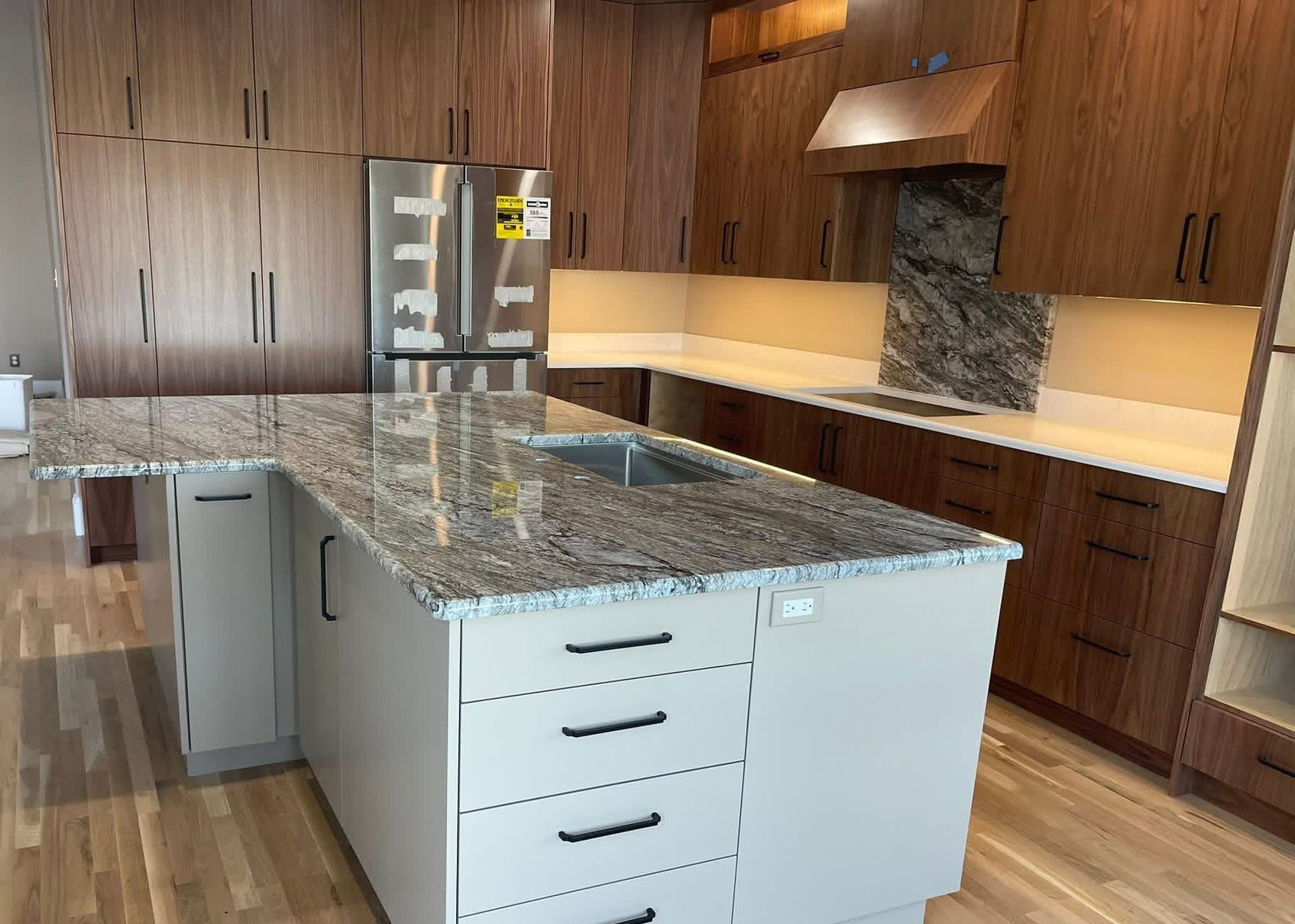 Wooden cabinetry in a kitchen area with a countertop, appliances, and a small bar with seating.