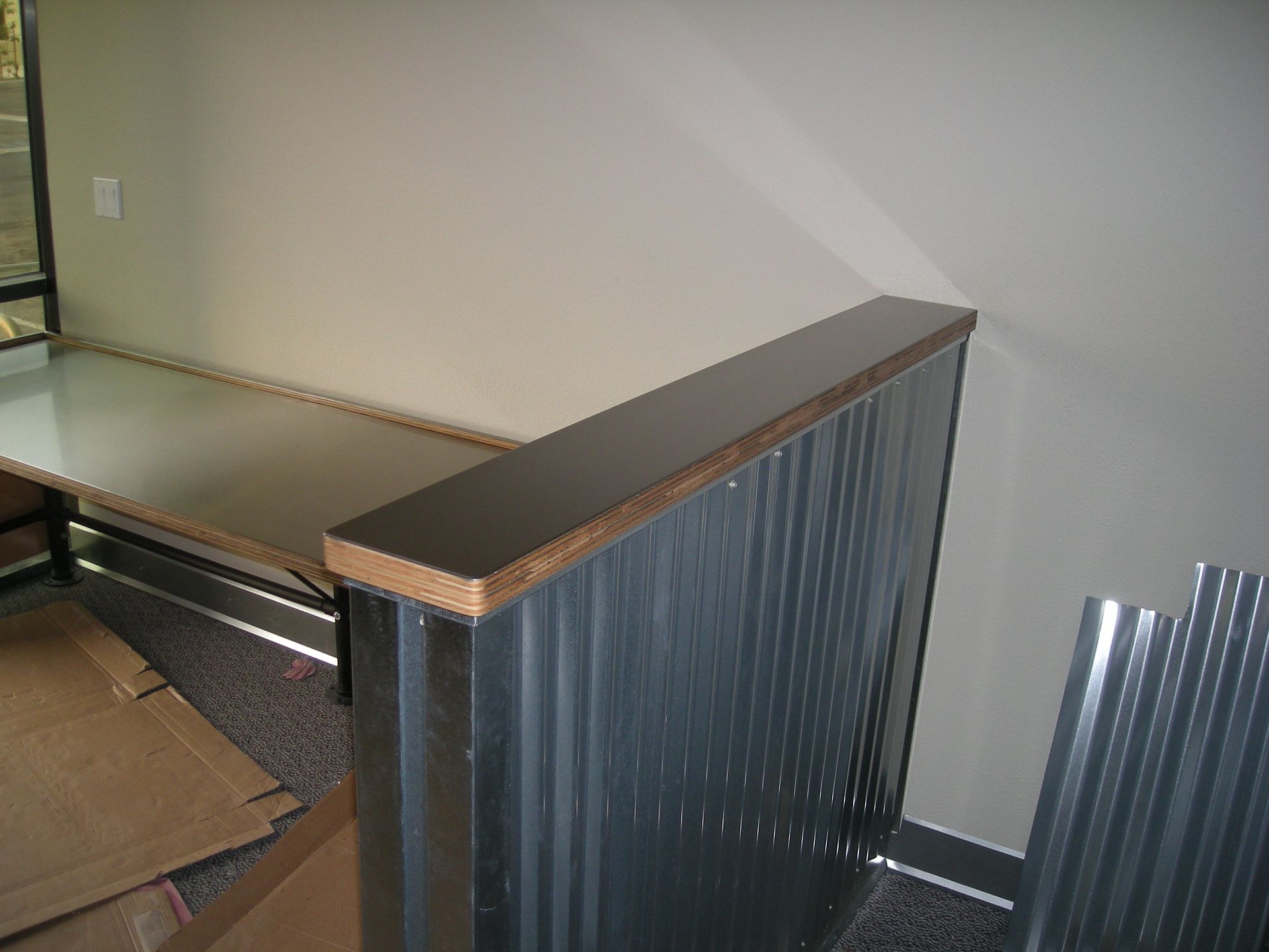 A desk with a corrugated metal divider and dark countertop in a building.