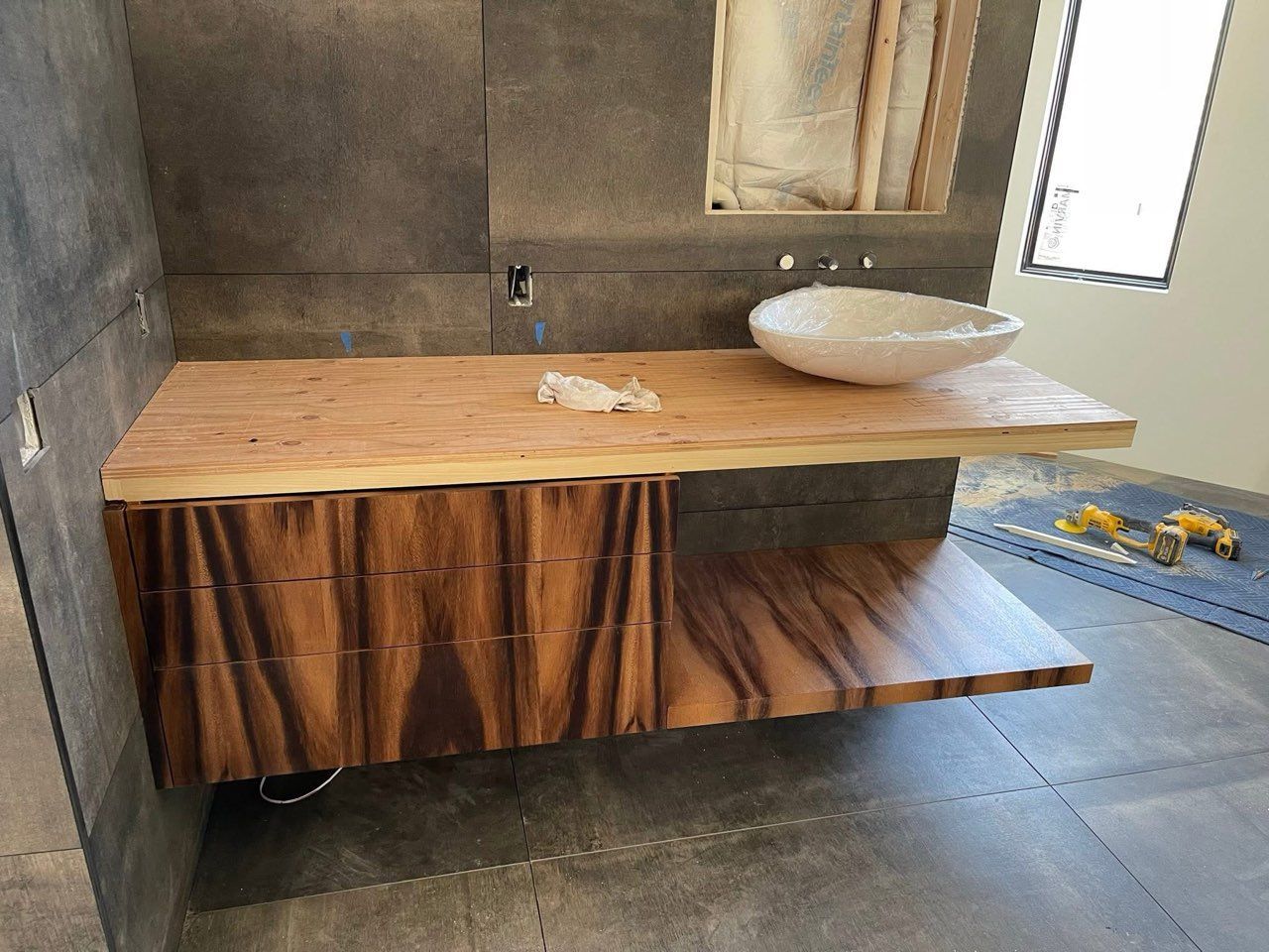 Wooden floating vanity with a vessel sink in a modern bathroom.