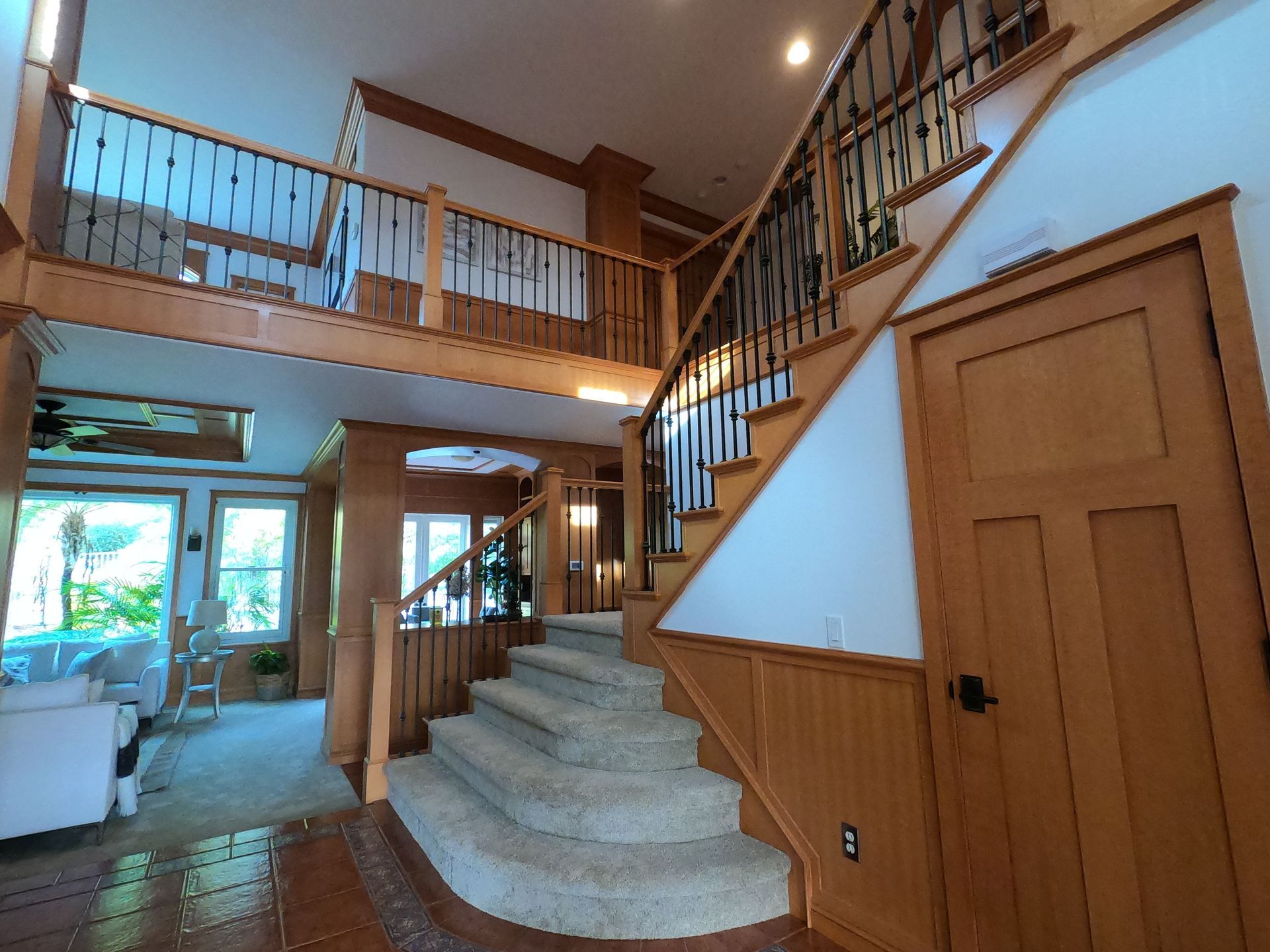 Interior view of a house with a staircase, wooden trim, and a loft.