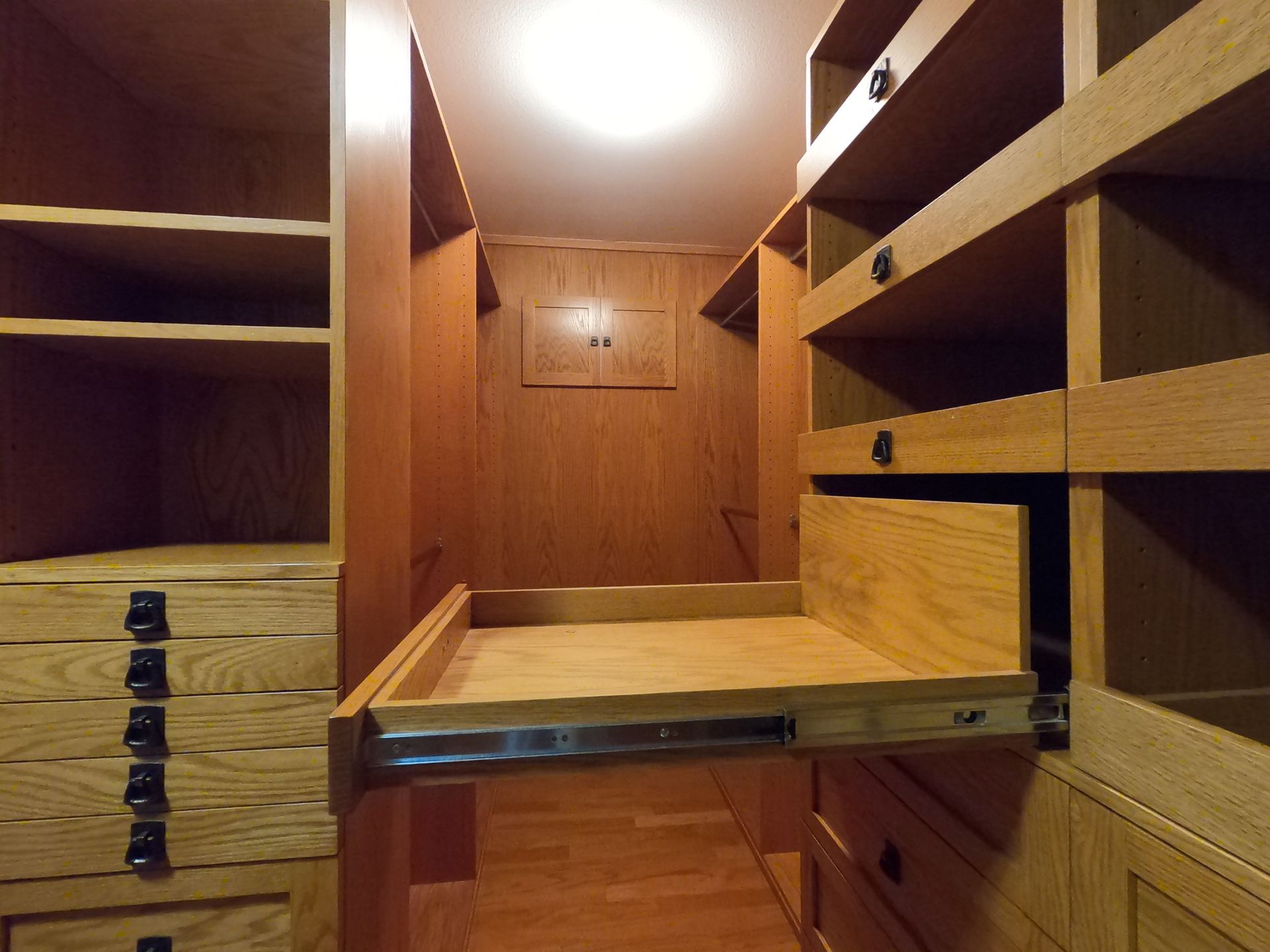 Wooden walk-in closet with open drawers and shelves. Light wood with metal drawer slides.