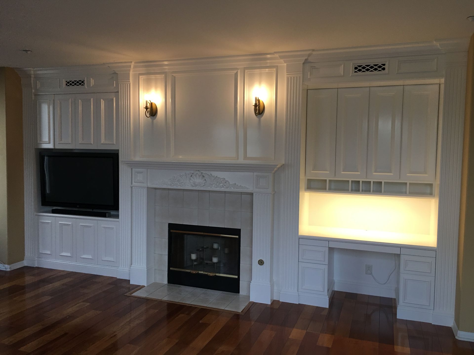 White built-in cabinetry surrounds a fireplace and TV. 