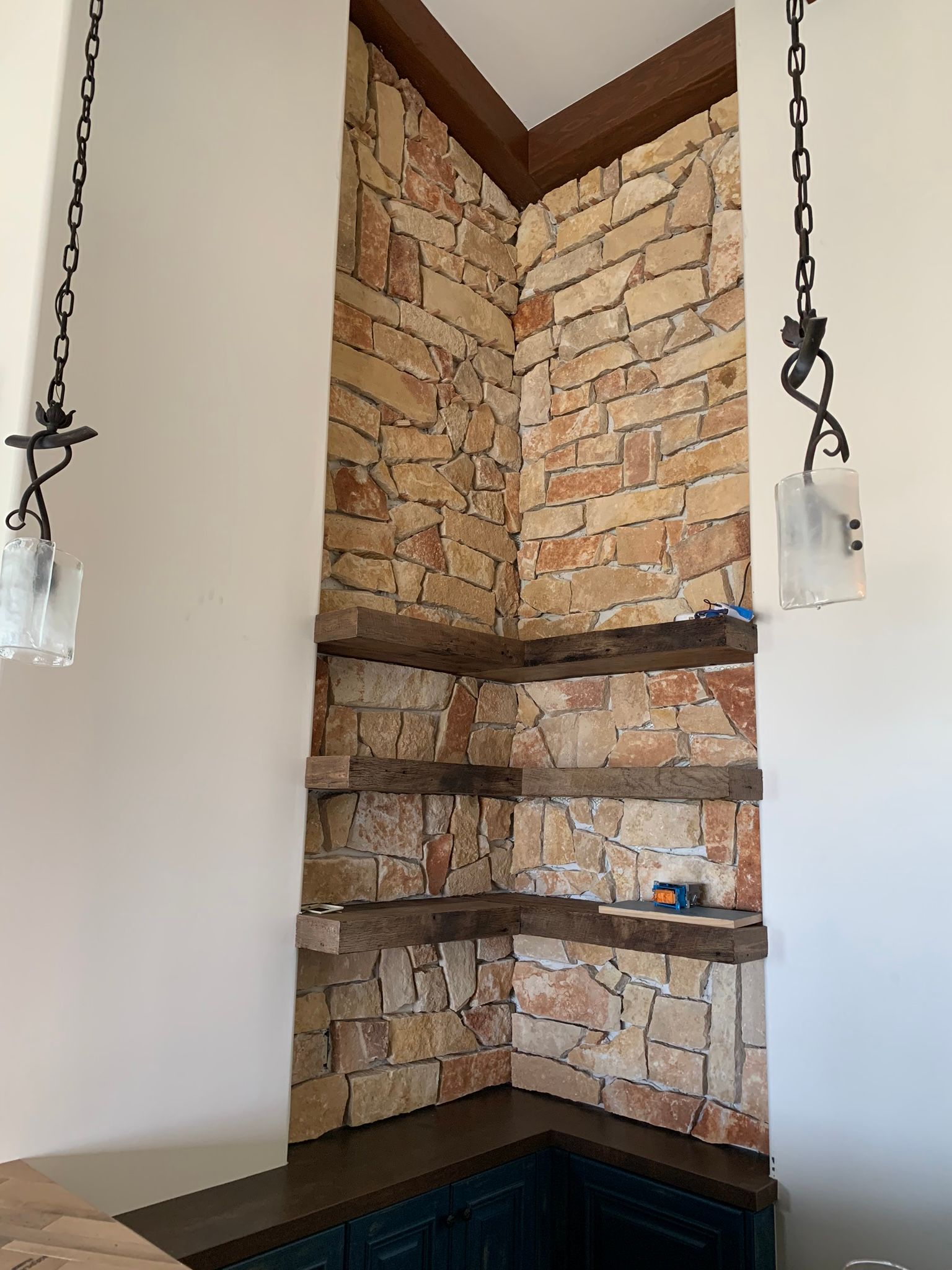 Corner with stone brick, wooden shelves, and hanging lights.