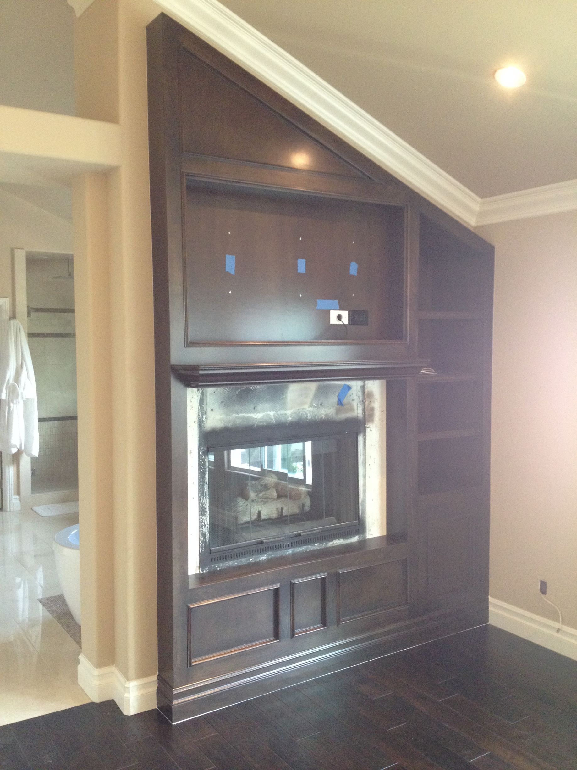 Dark wood fireplace and entertainment center built into a wall, with a TV space and shelves.