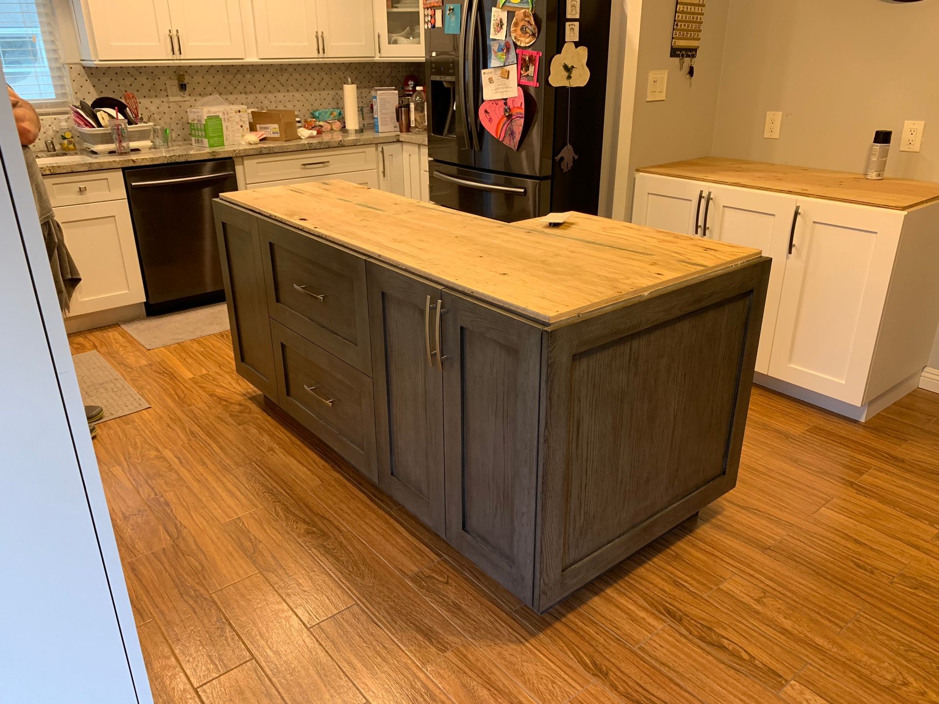 Kitchen with a gray island and light wood countertop, white cabinets, and wooden floors.