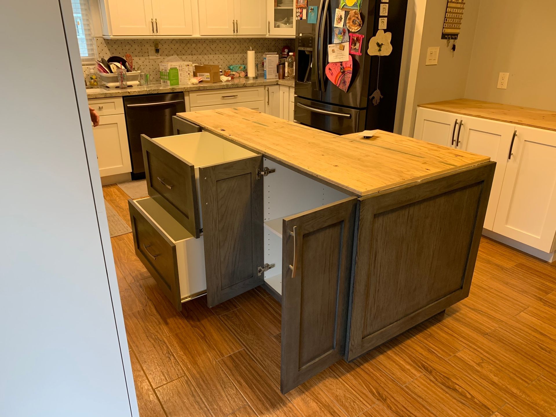 Kitchen island with gray cabinets and wood countertop; drawer and cabinet open.