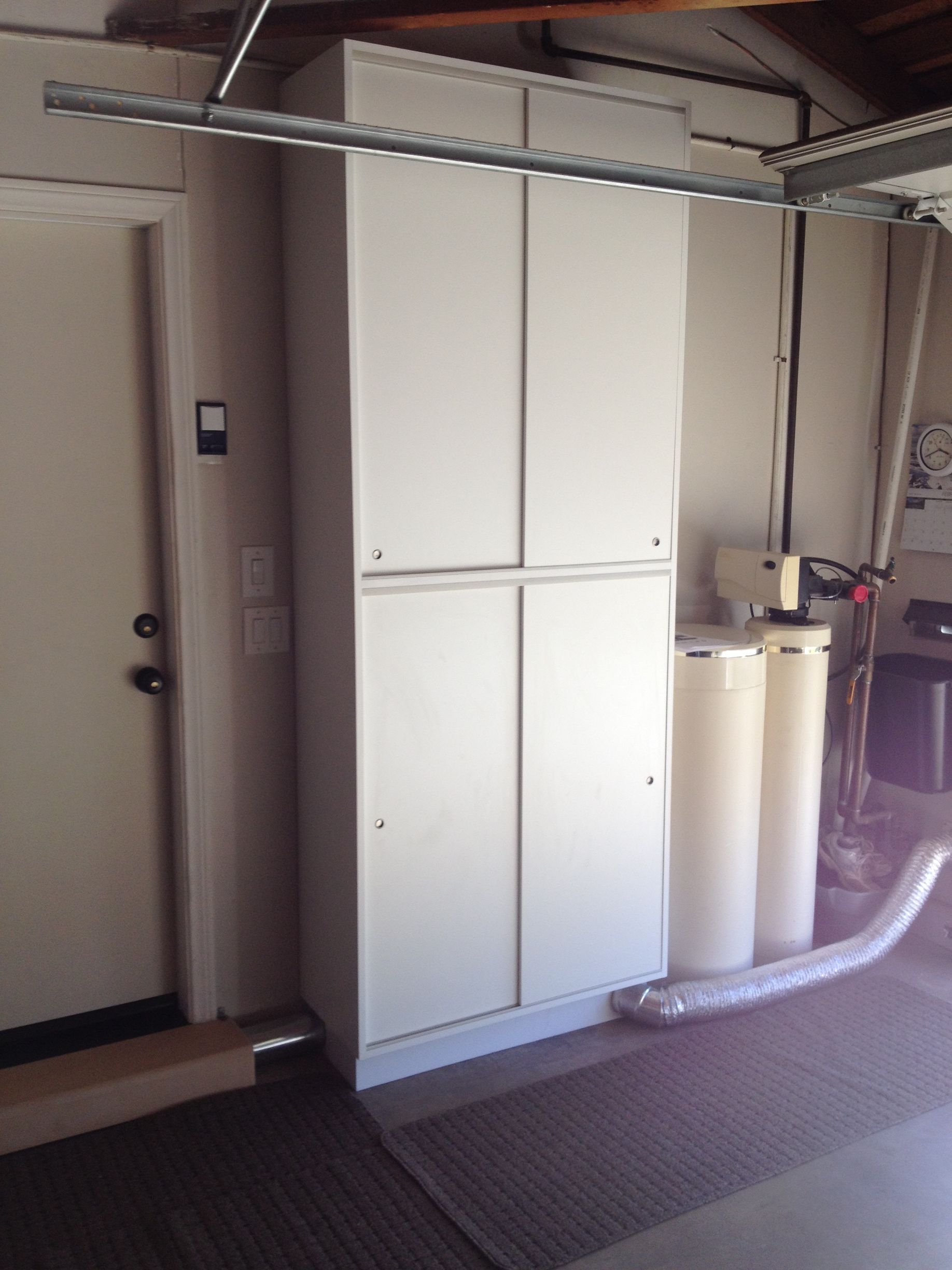 Garage storage cabinet next to a door, water filter, and garage door track.