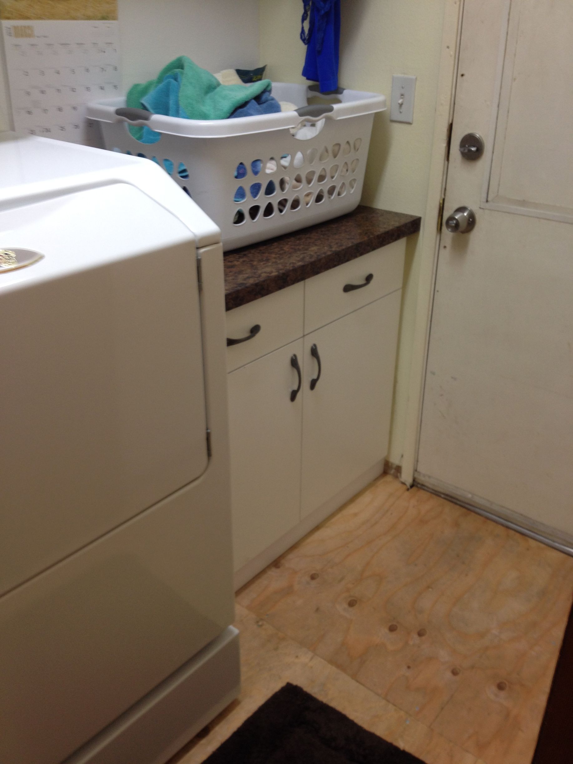 Laundry room with a washing machine, cabinet, and laundry basket.