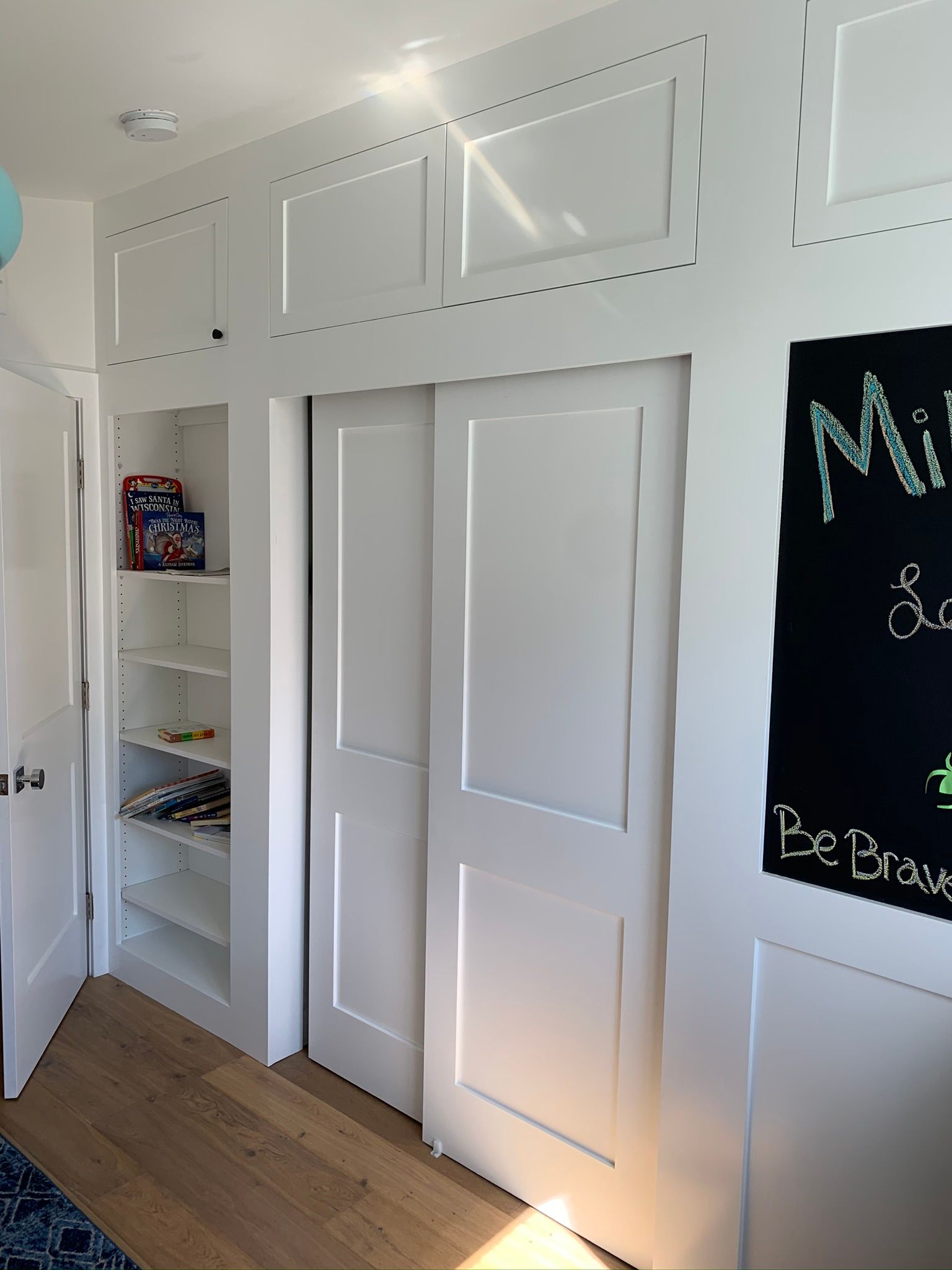 White closet with sliding doors, built-in shelves, and decorative wall panels.