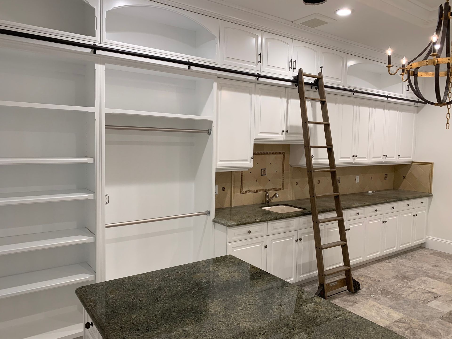 White kitchen cabinetry with a ladder and granite countertop.