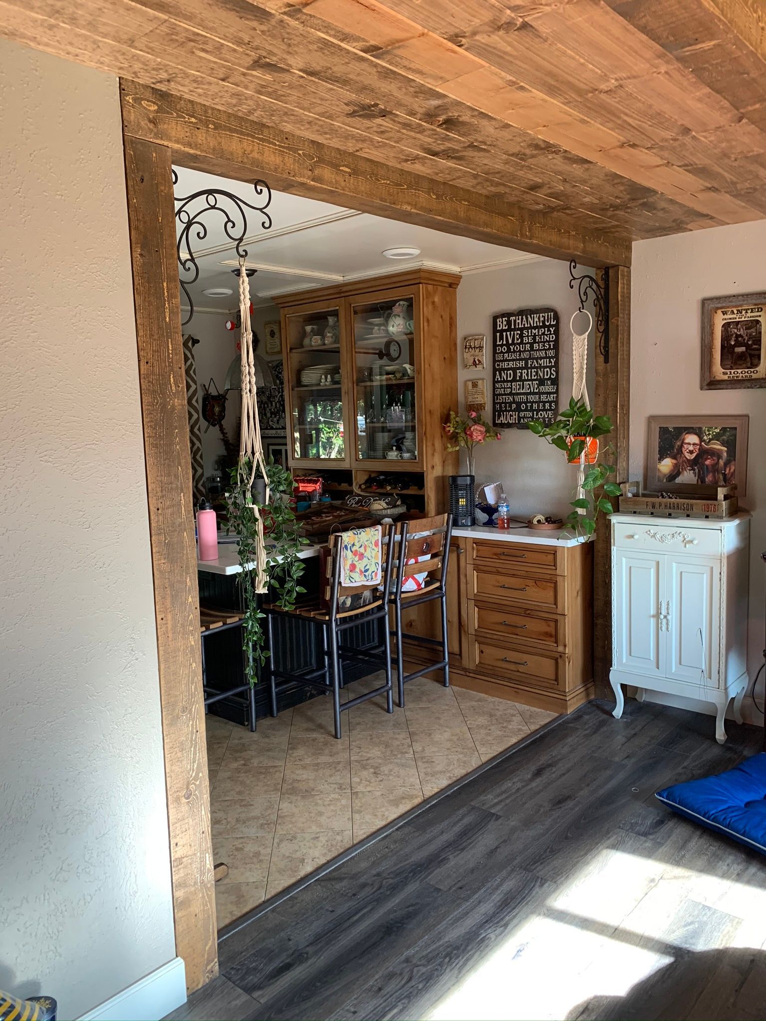 Wooden doorway leads to a kitchen with wooden cabinets, a table, and a small white cabinet.