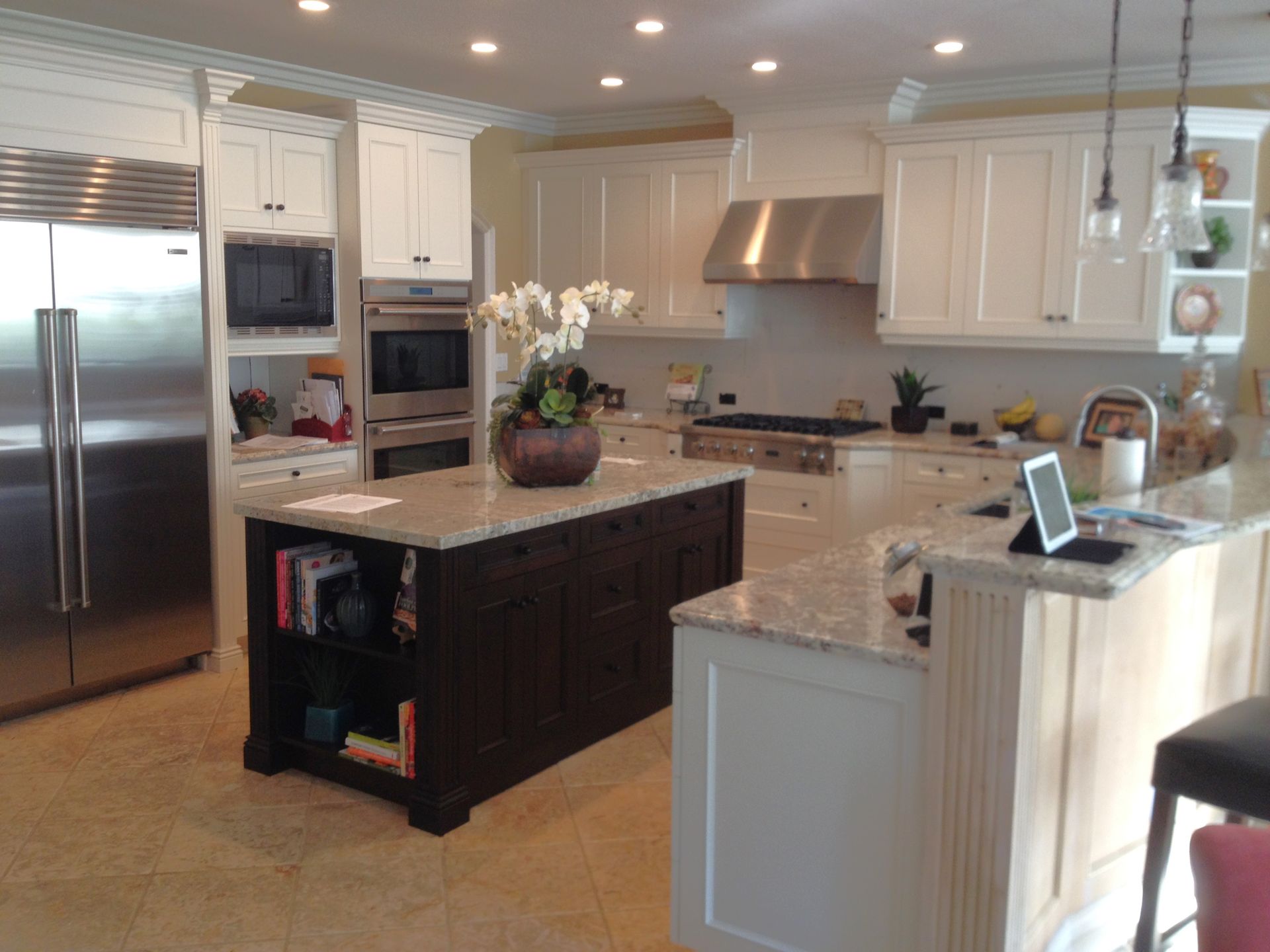 White kitchen with a dark island, granite countertops, and stainless steel appliances.