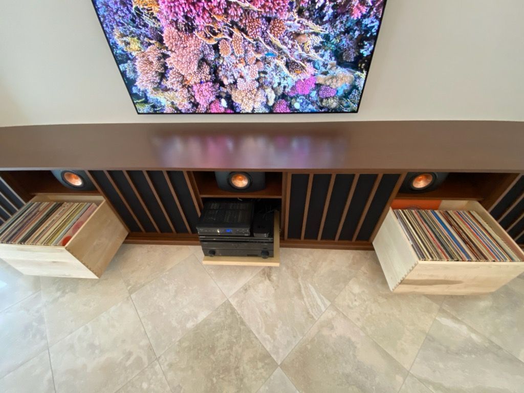 Entertainment center with TV, speakers, record storage, and audio equipment. Brown and beige tones.