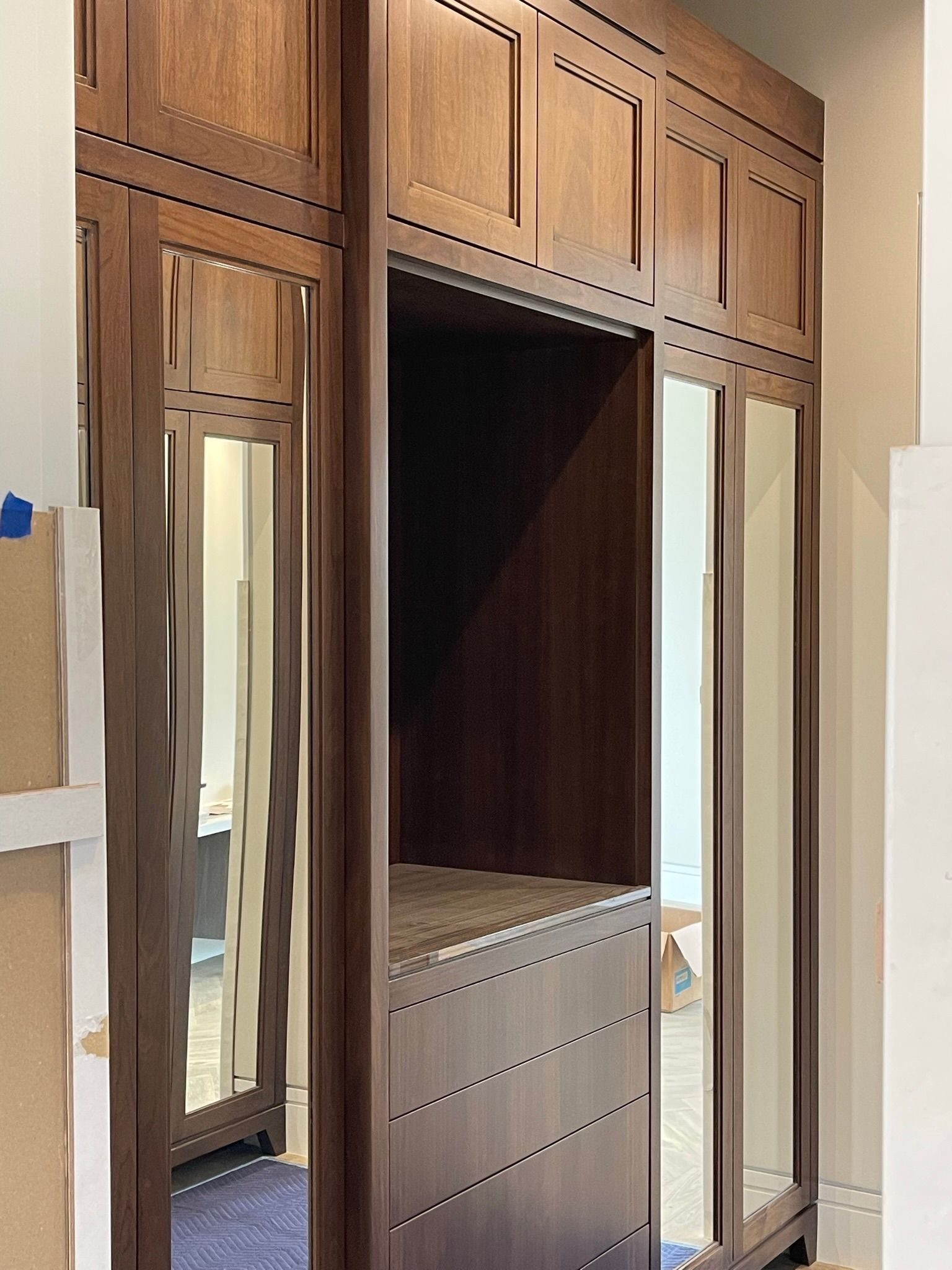 Wooden closet with mirror panels and an open center section. Brown wood, interior room.