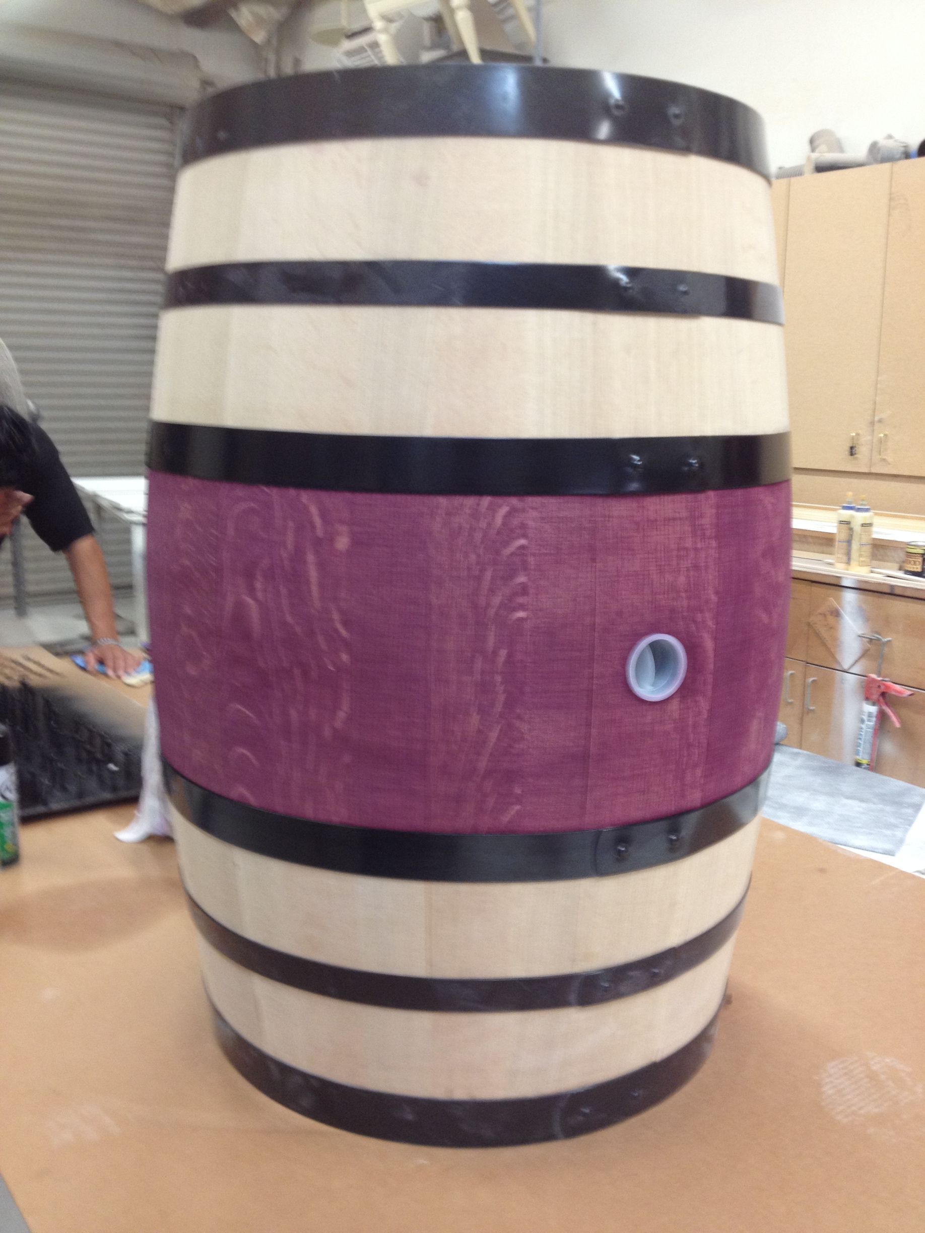 Wooden barrel with alternating light and dark bands, purple center, and a spigot.