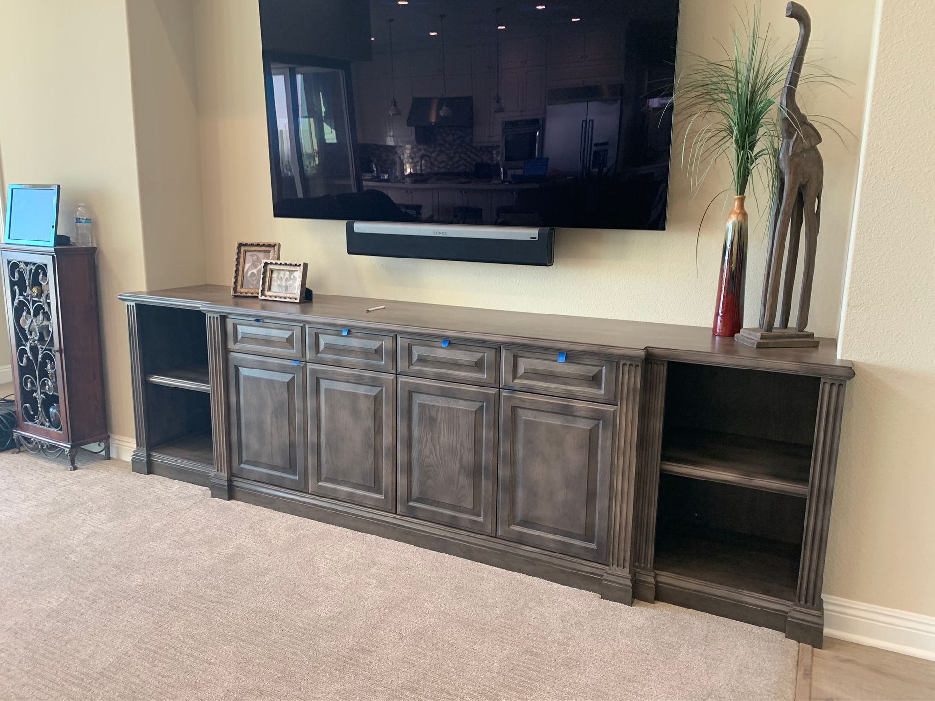 Built-in wooden entertainment center with TV, soundbar, and decorative objects.