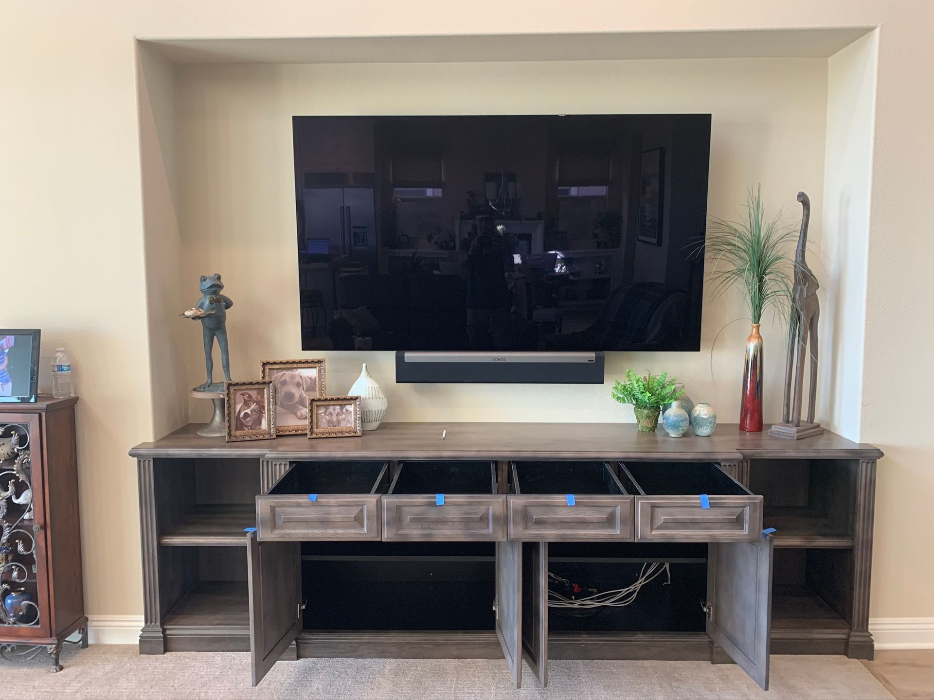 Entertainment center with mounted TV, decorative items, and open cabinets.