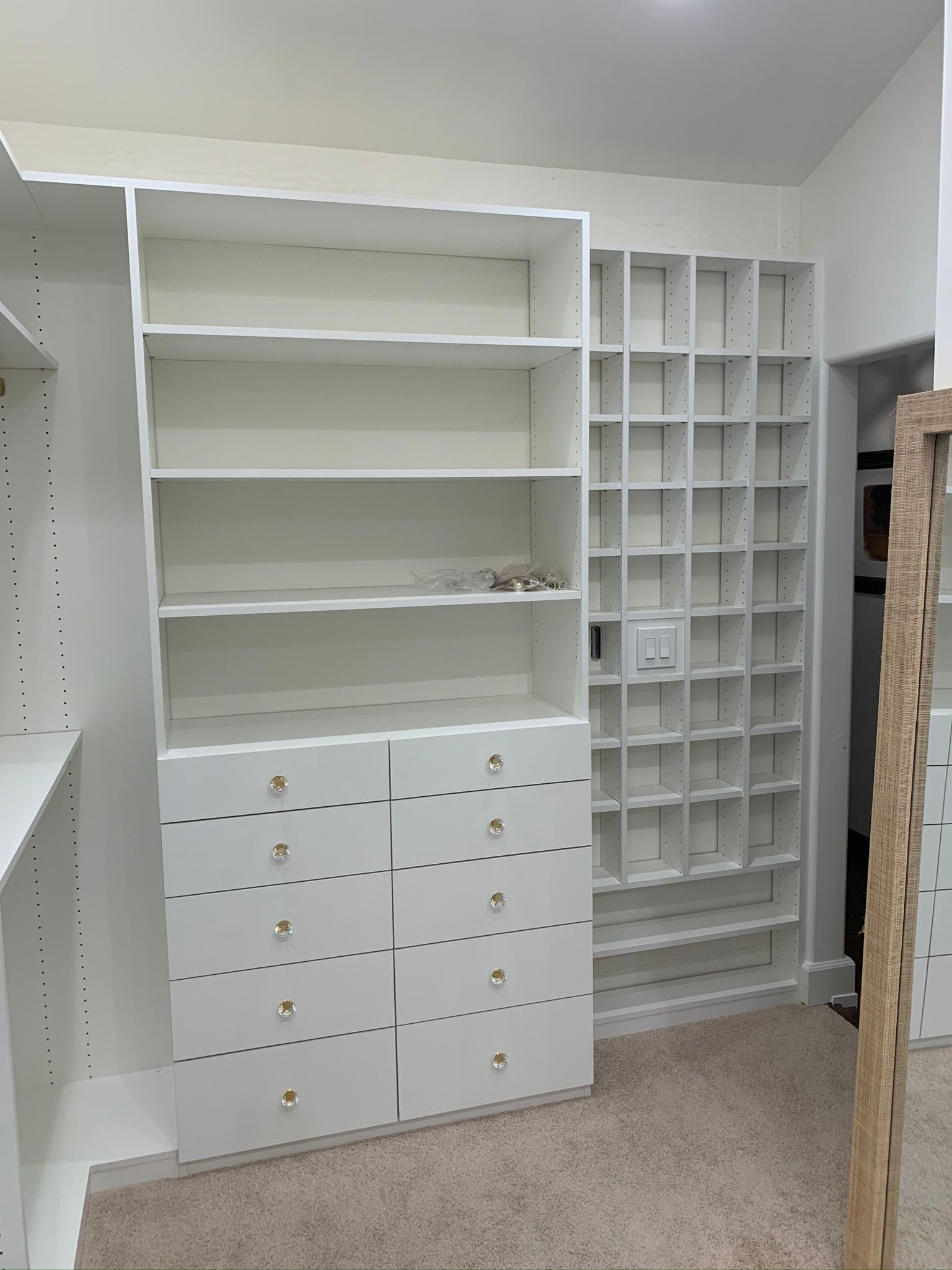 White closet shelving unit with drawers and cubbies in a room with carpet.
