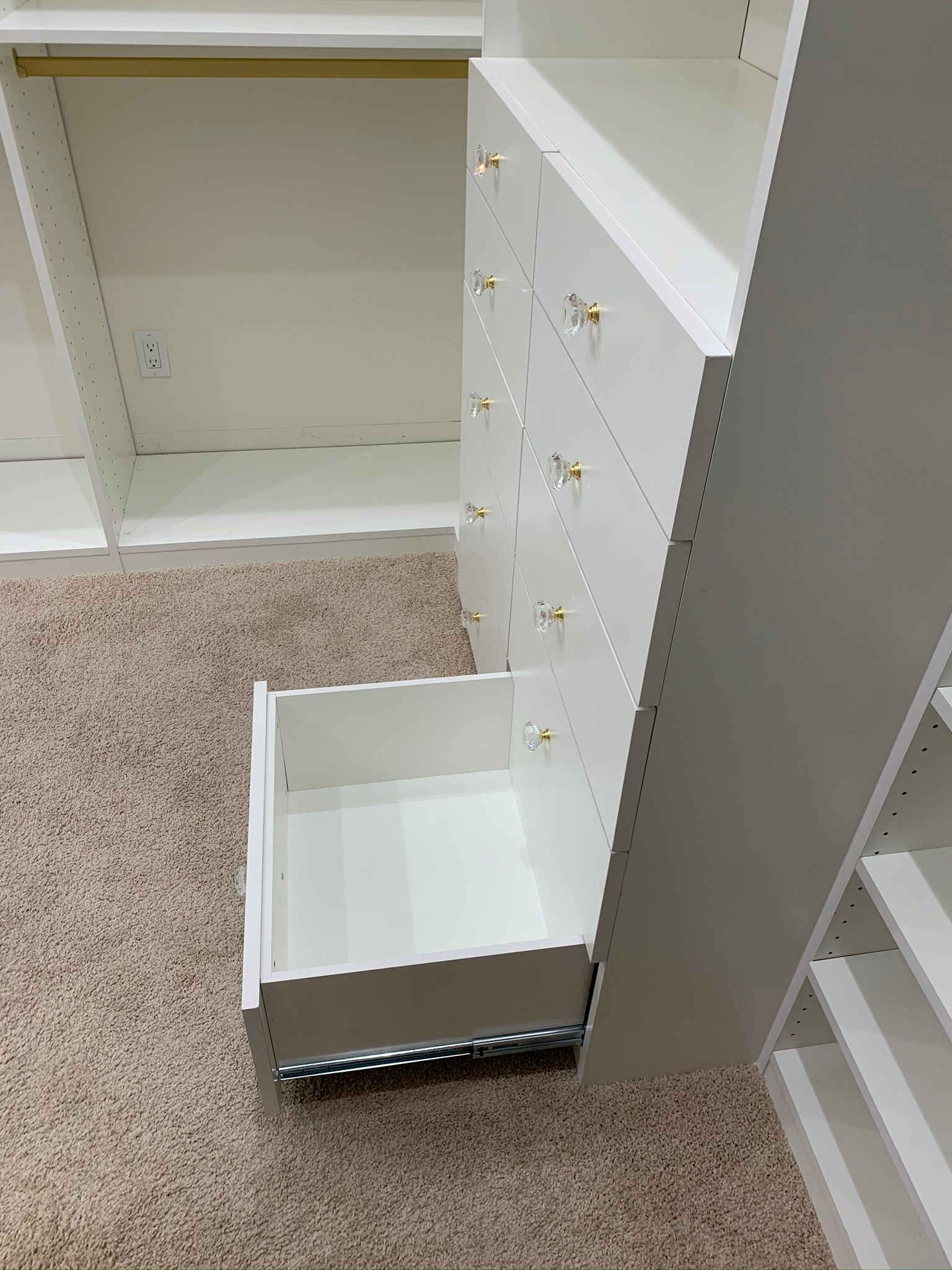 White closet with an open drawer on a carpeted floor.