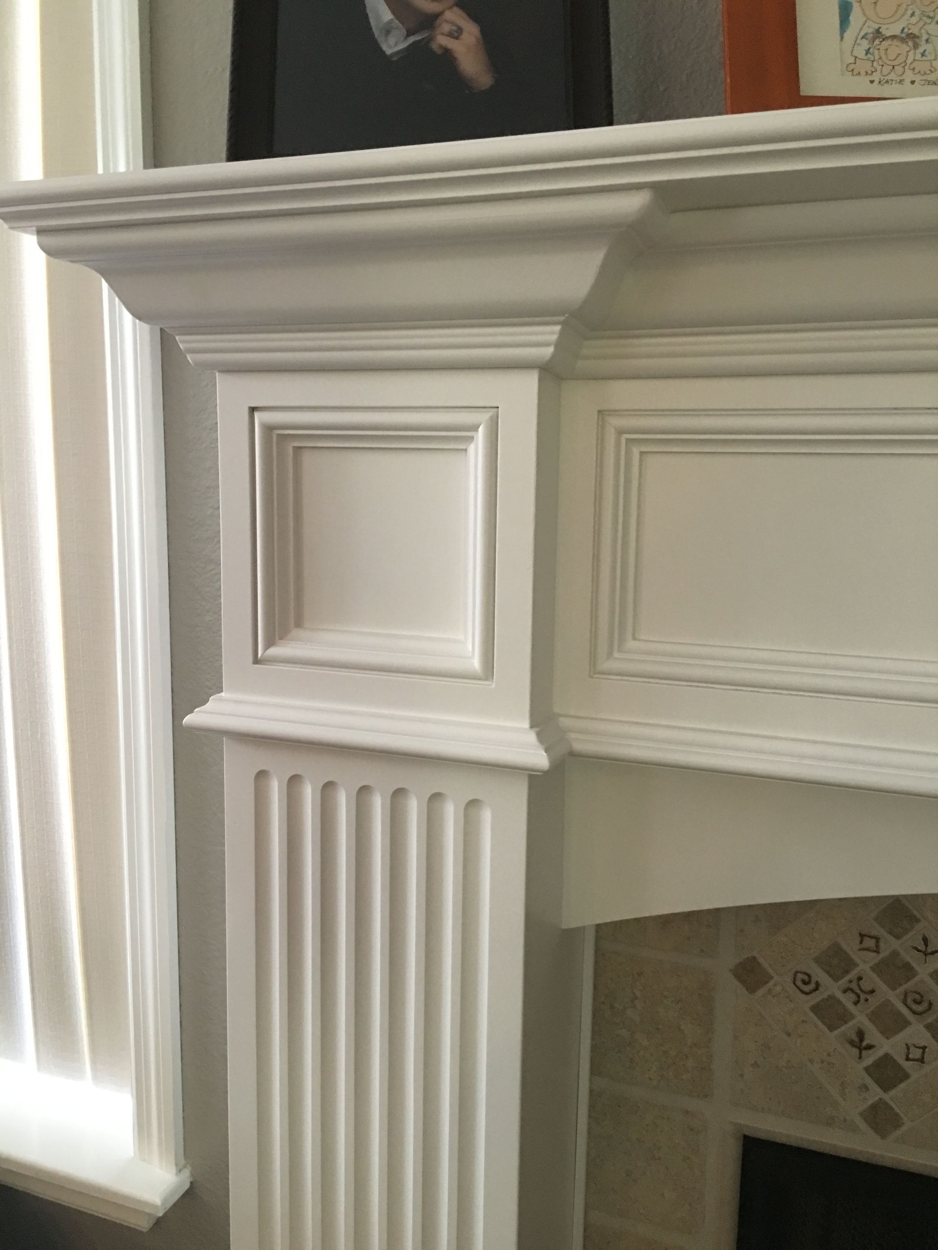 White fireplace mantel with square paneling, fluted details, and an off-white tile hearth.