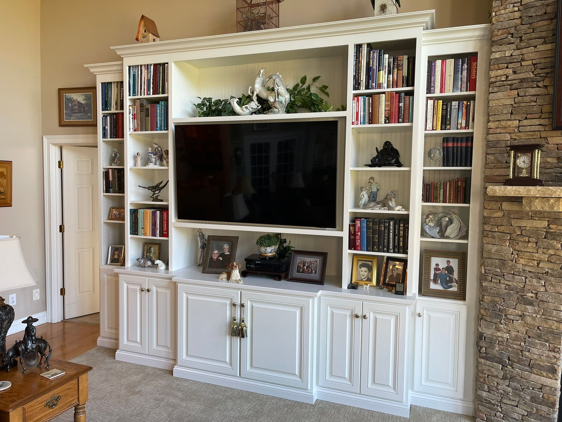 White built-in shelving unit with TV, books, and decorative items.