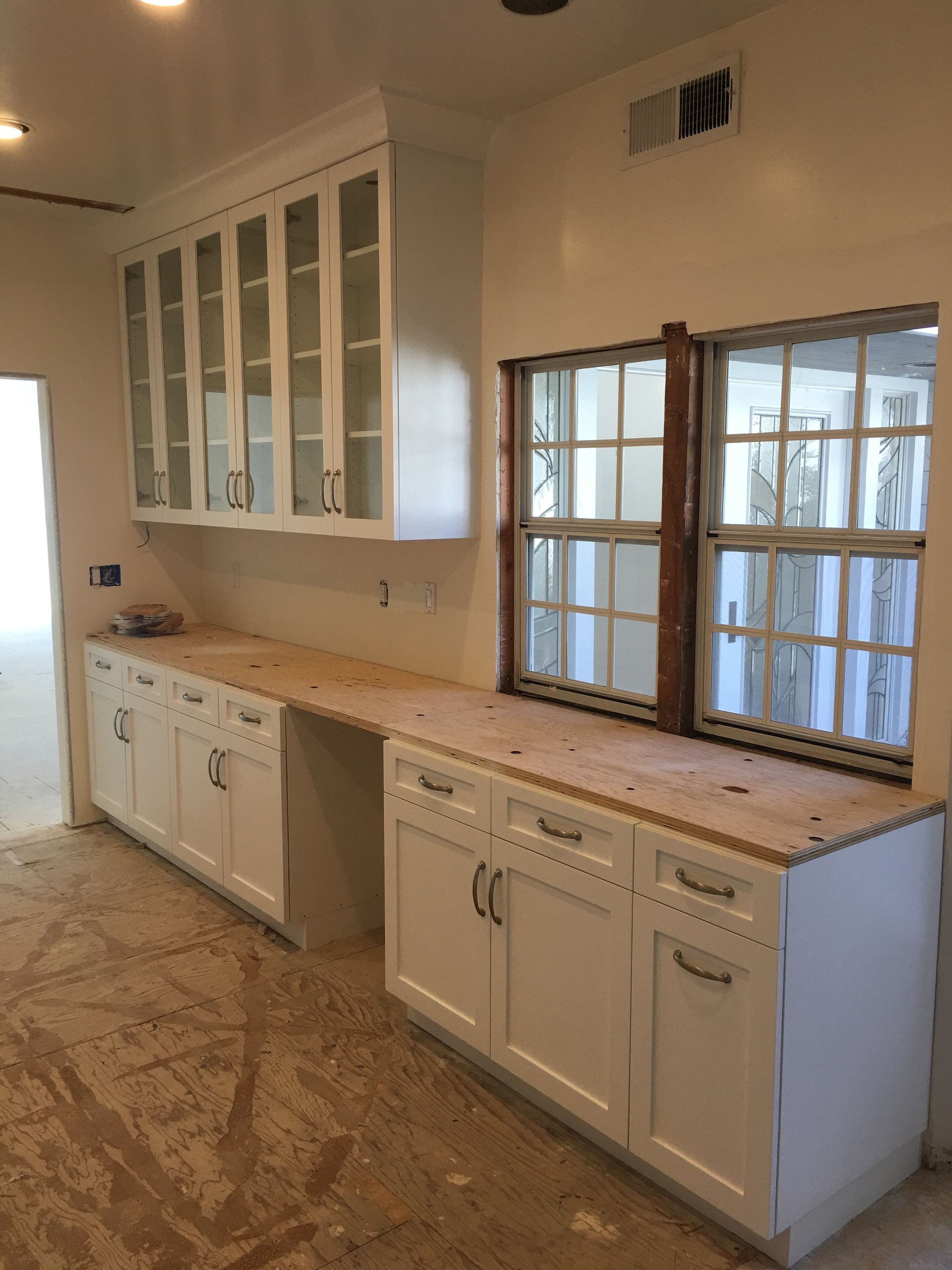 White kitchen cabinets and counters; windows in background.
