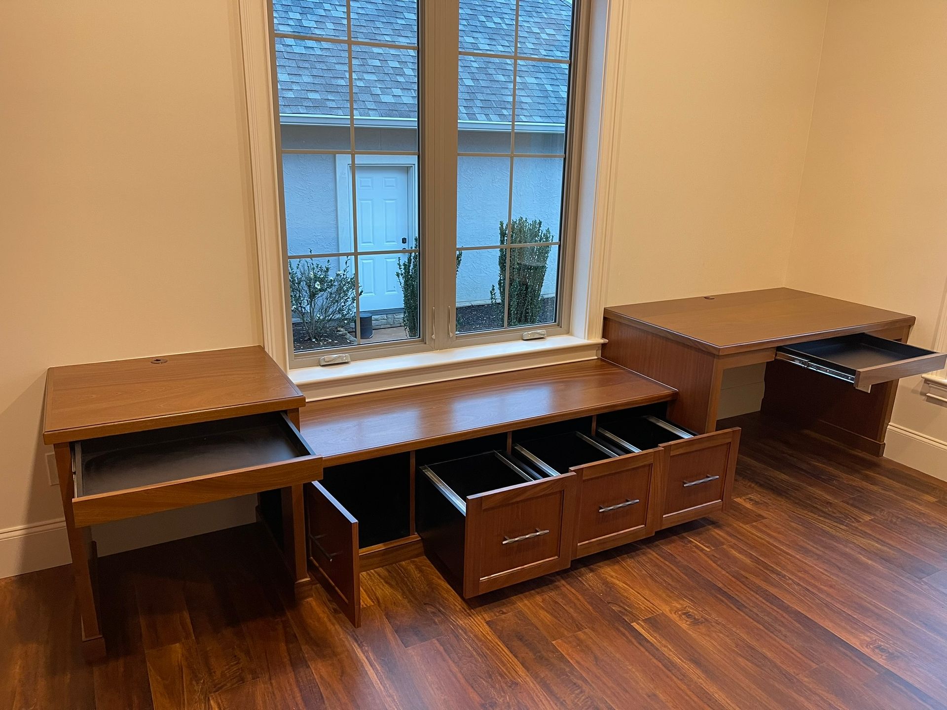 Wooden office furniture set with drawers open, by a window.