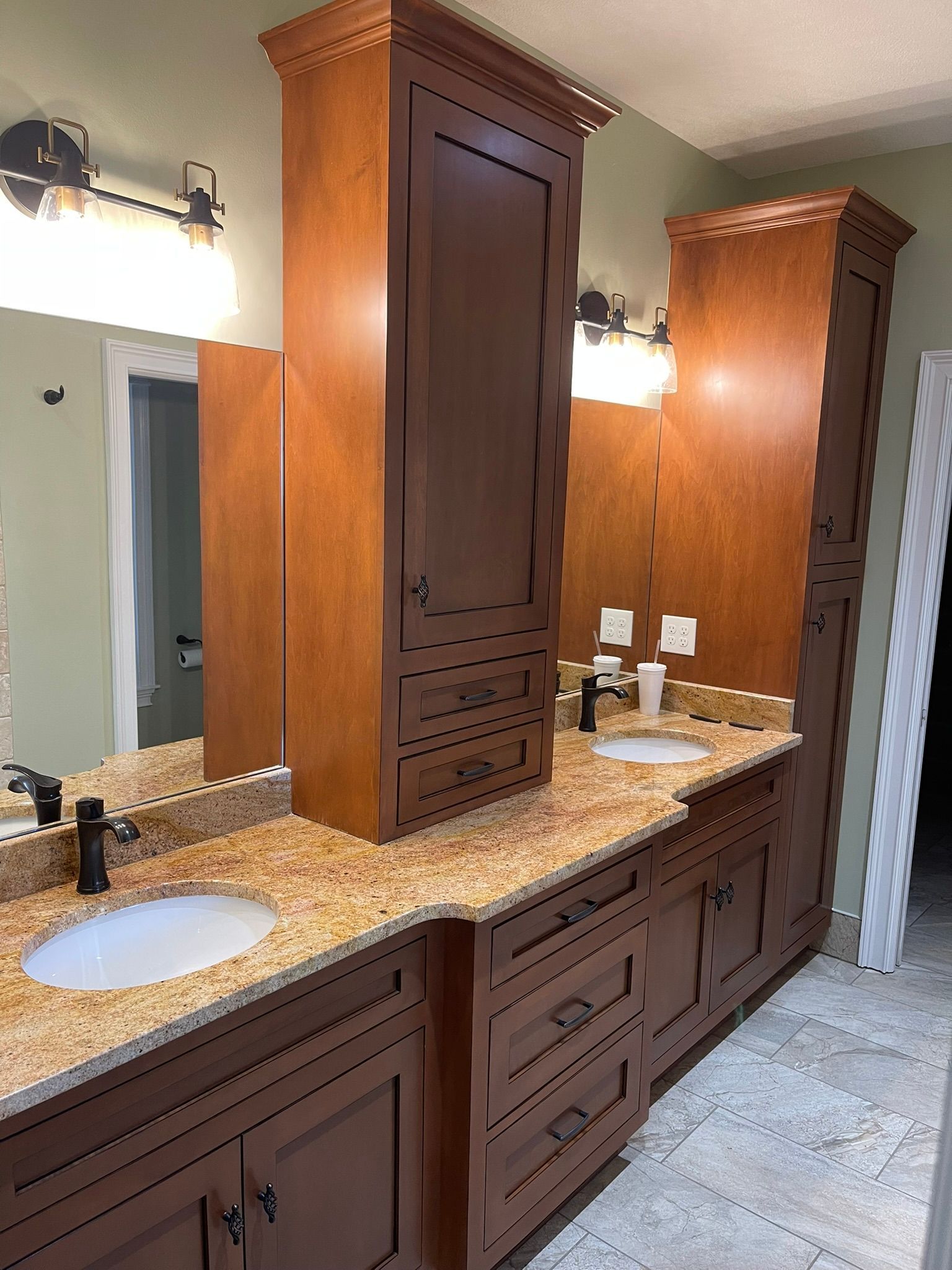 Bathroom vanity with brown cabinets, granite countertops, and two sinks.