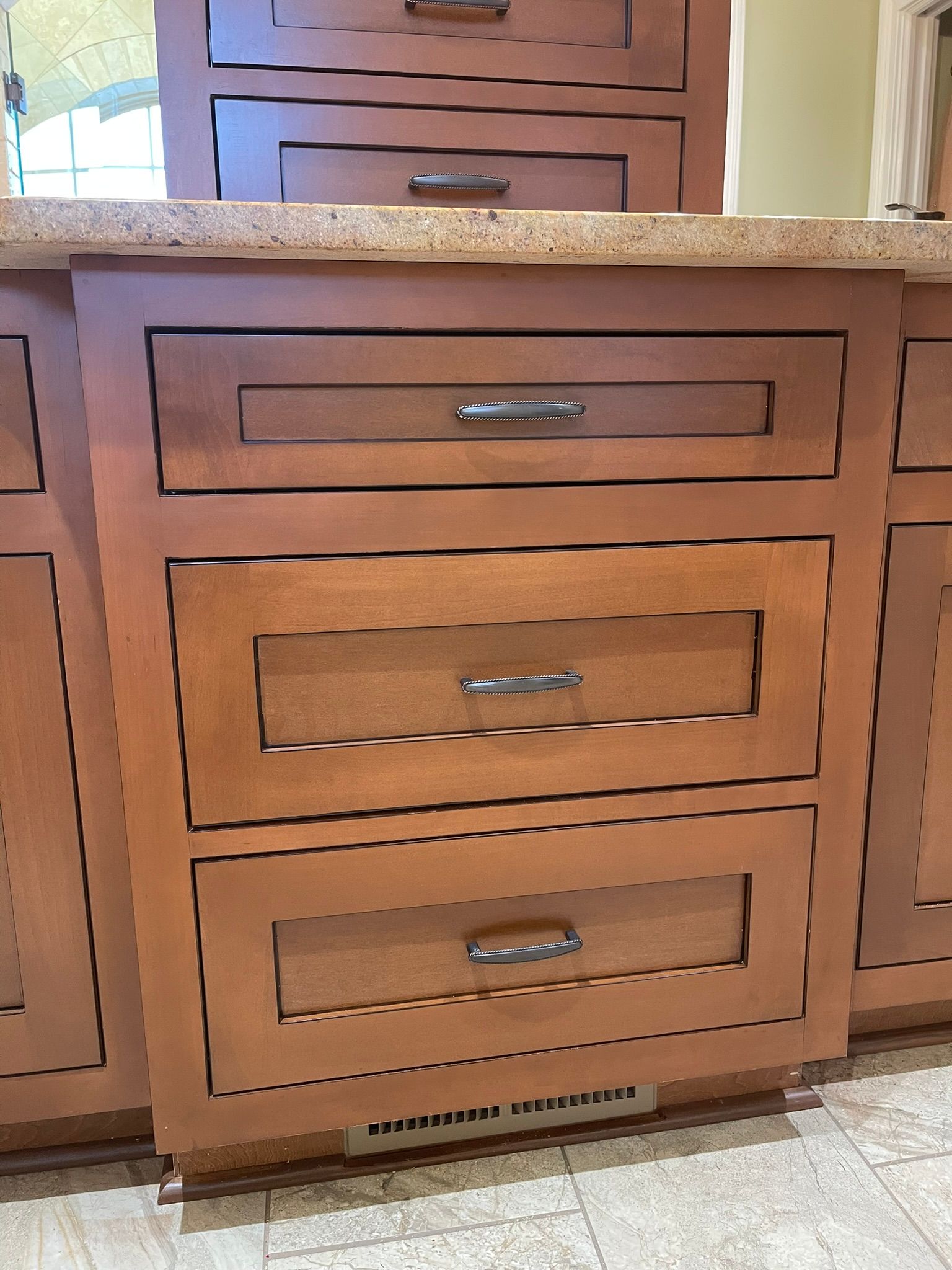 Wooden kitchen drawers with silver handles, brown countertop.