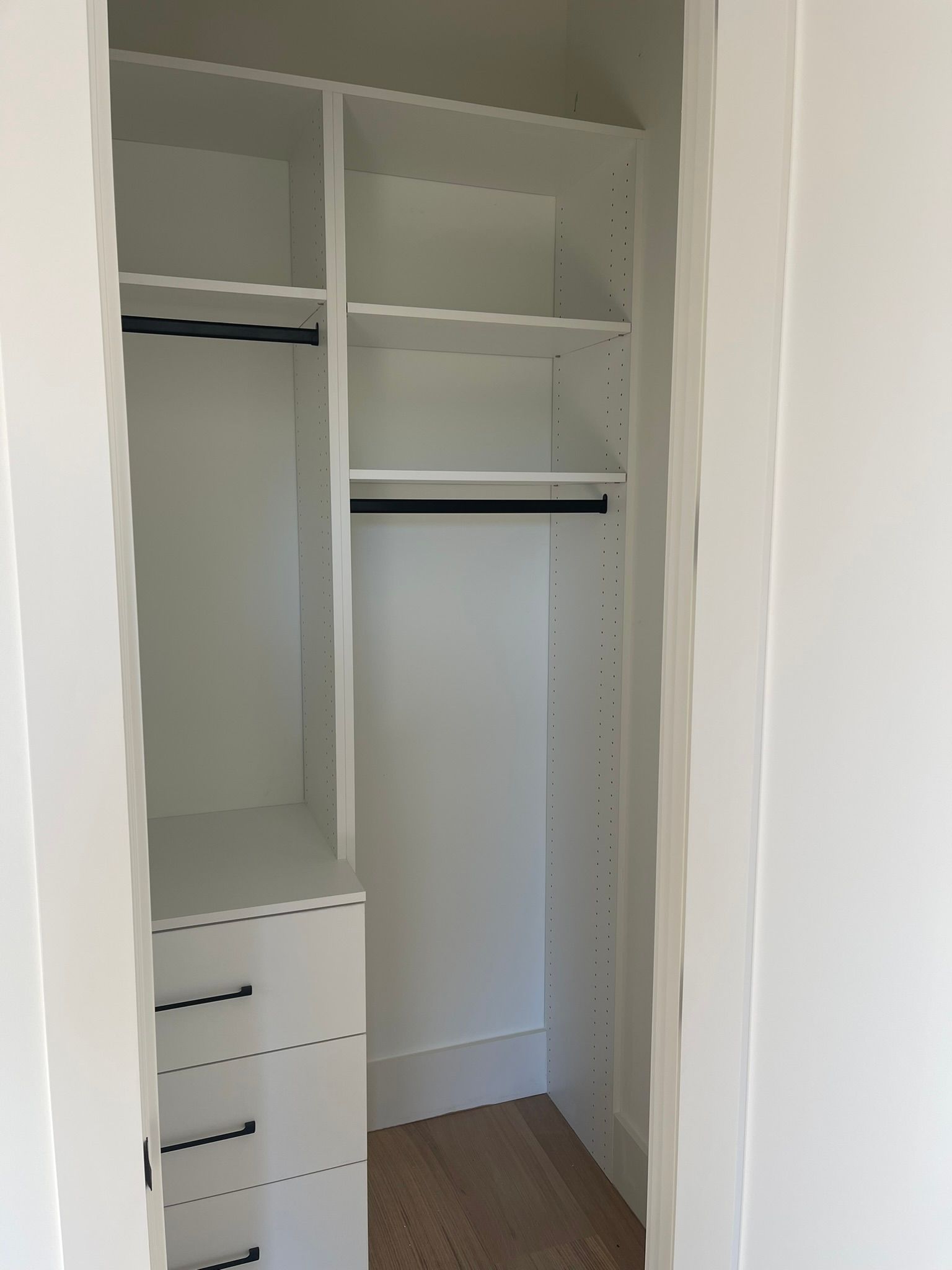 White closet with drawers, shelves, and hanging rods. Interior view.