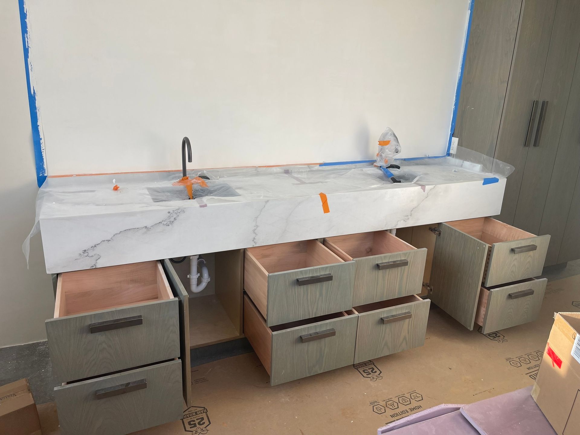 Bathroom vanity with marble countertop and open drawers; a black faucet is on the left.