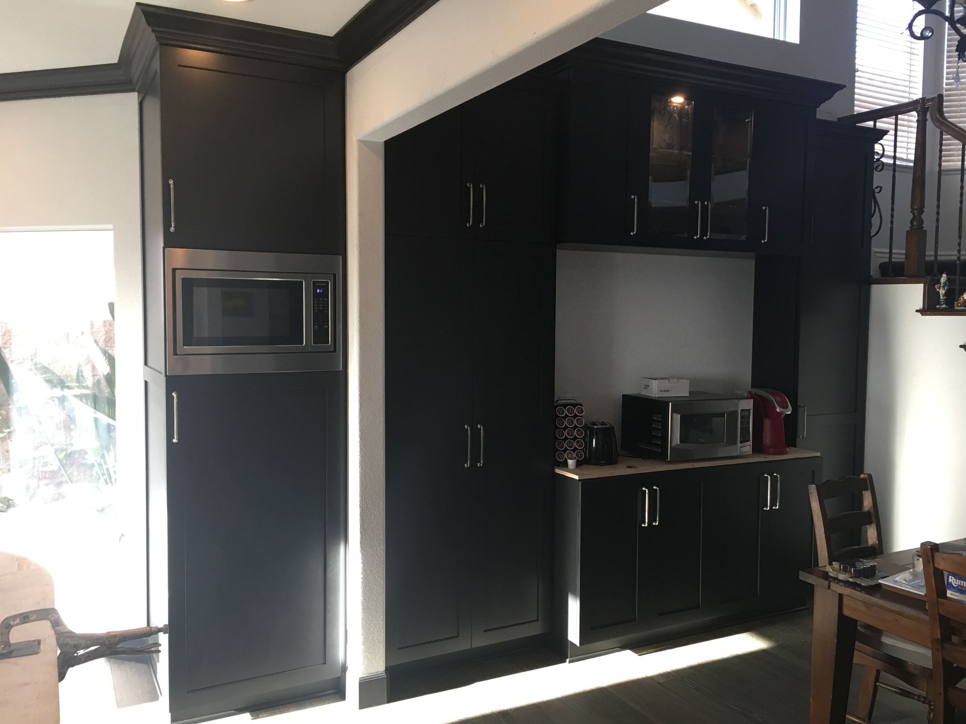 Dark kitchen cabinets with a microwave and coffee station.