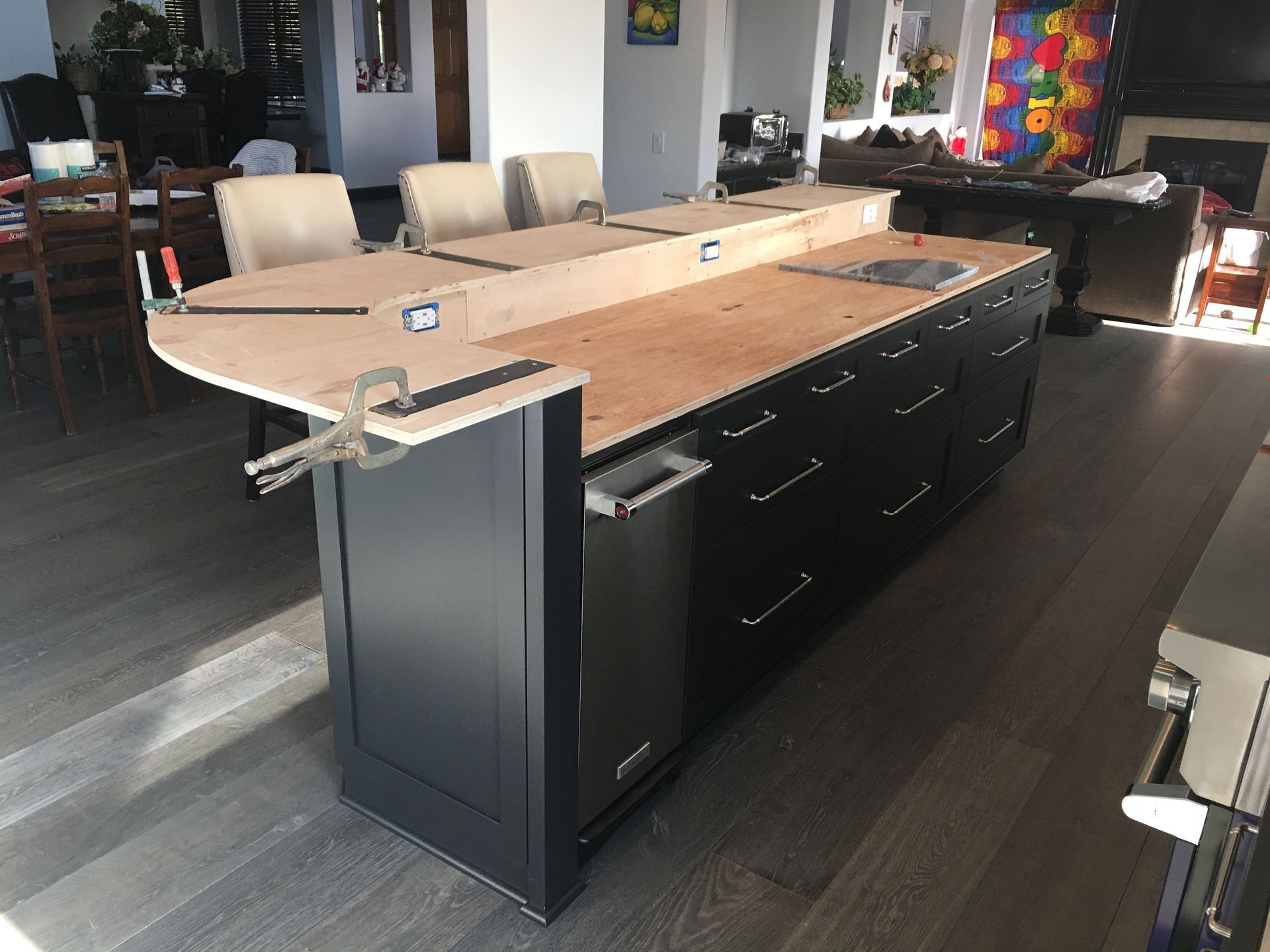 Black kitchen island under construction with light wood countertop.