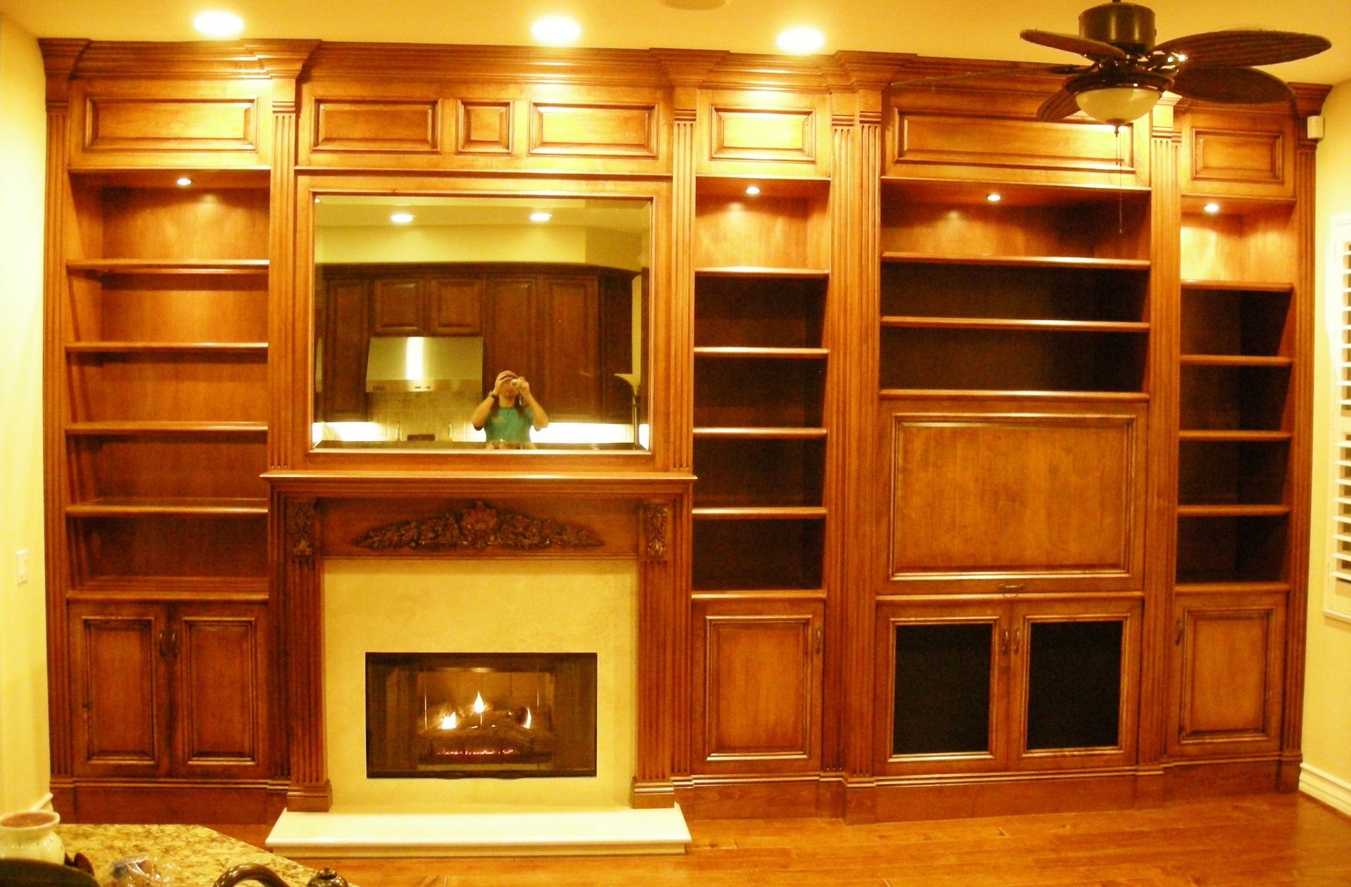 Built-in wooden entertainment center with fireplace, bookshelves, and recessed lighting.
