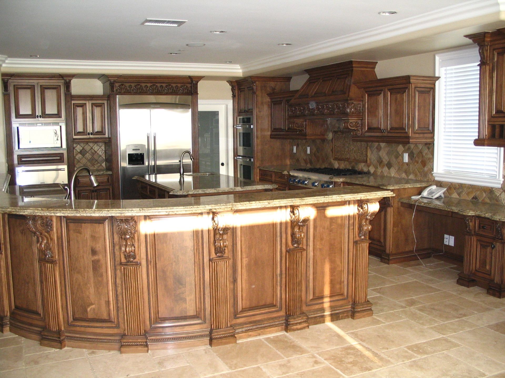 Luxurious kitchen with dark wood cabinetry, granite countertops, and stone backsplash.