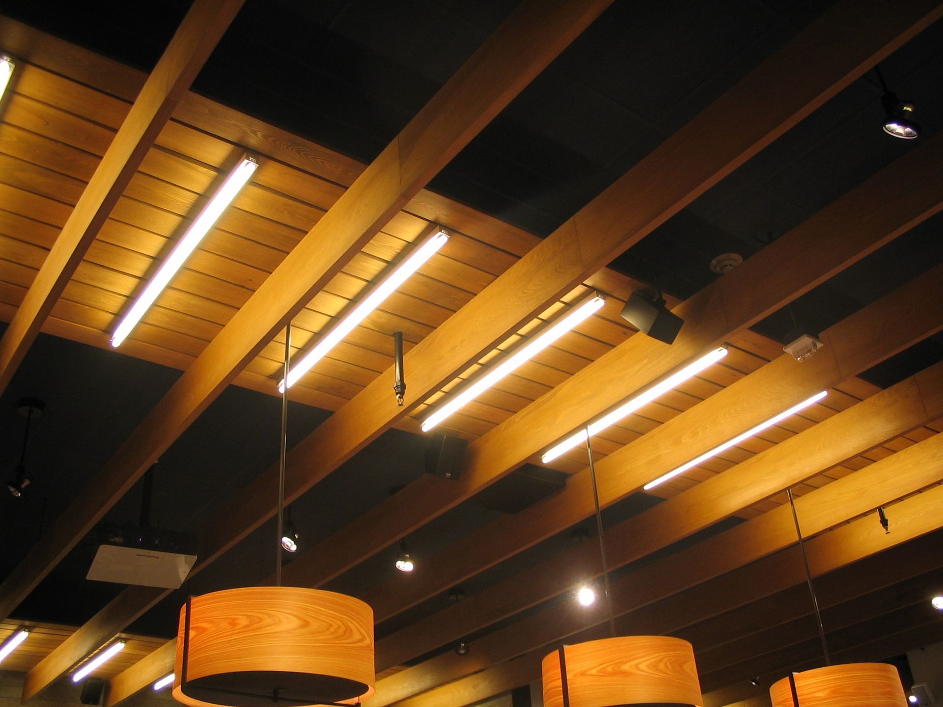 Wooden ceiling with recessed lighting and hanging pendant lamps.