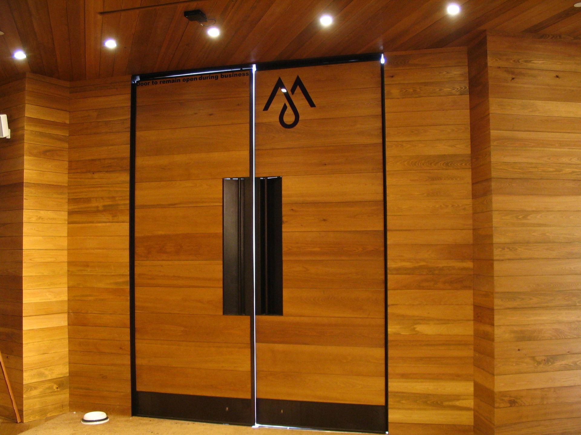Wooden double doors with black trim and a symbol.