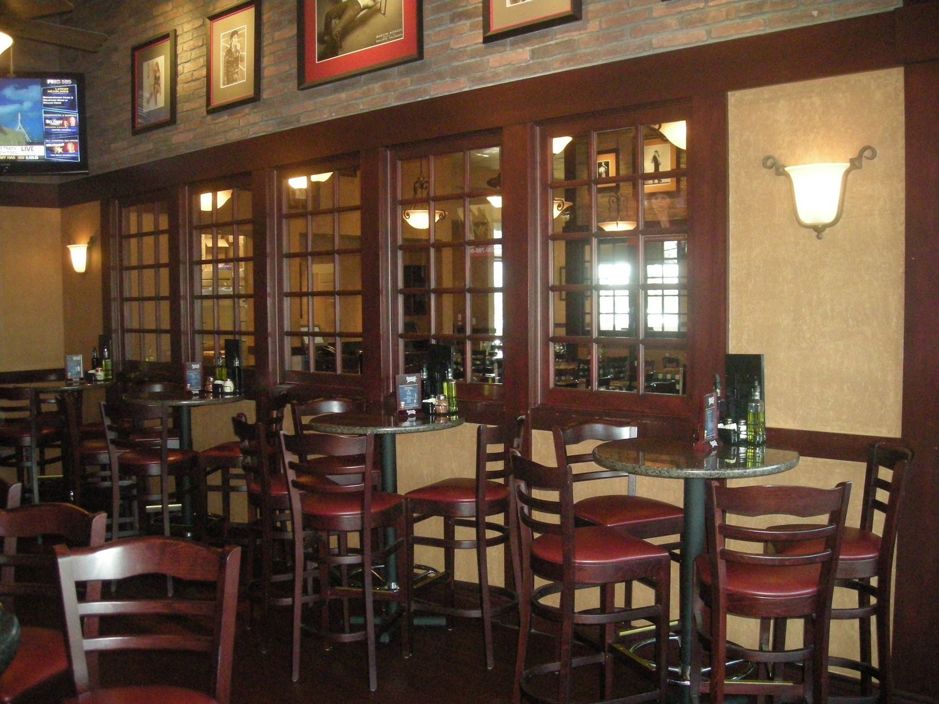 Interior of a restaurant with high-top tables, chairs, and dark wood trim. Decorative wall sconces and framed art.