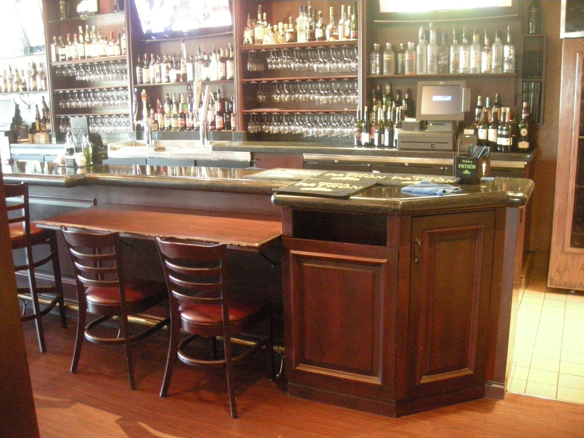 Bar interior with seating, dark wood cabinets, and shelves stocked with alcohol.