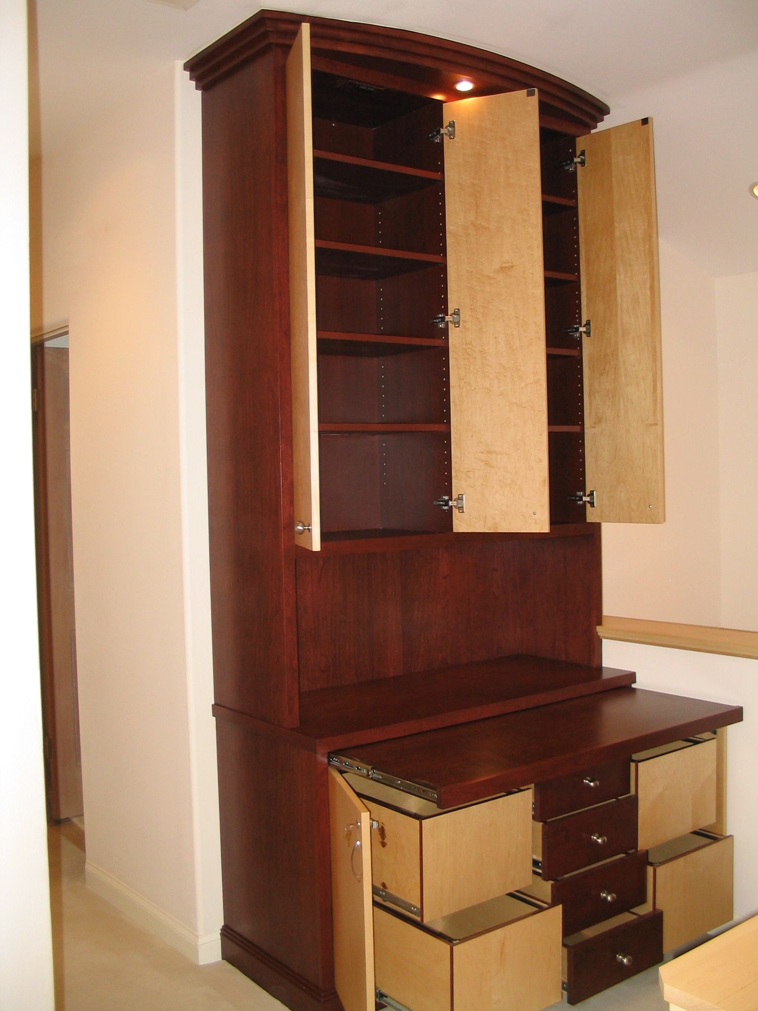 Tall, dark wood cabinet with open doors and drawers. Interior shelves, desk surface, and drawers are visible.