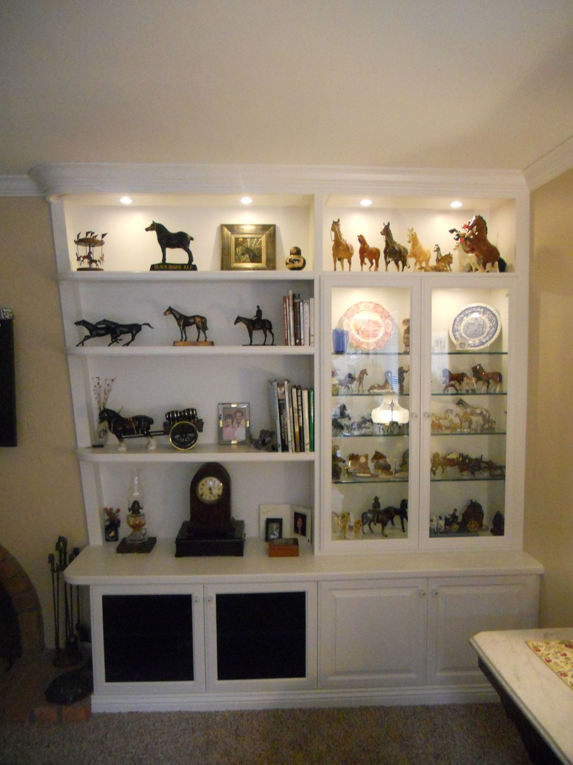 White display cabinet with horse figurines, books, and decorative items.