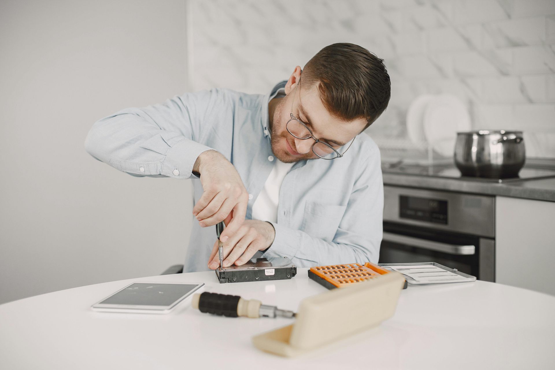 Technician repairing a smartphone at a workbench with tools and small parts nearby