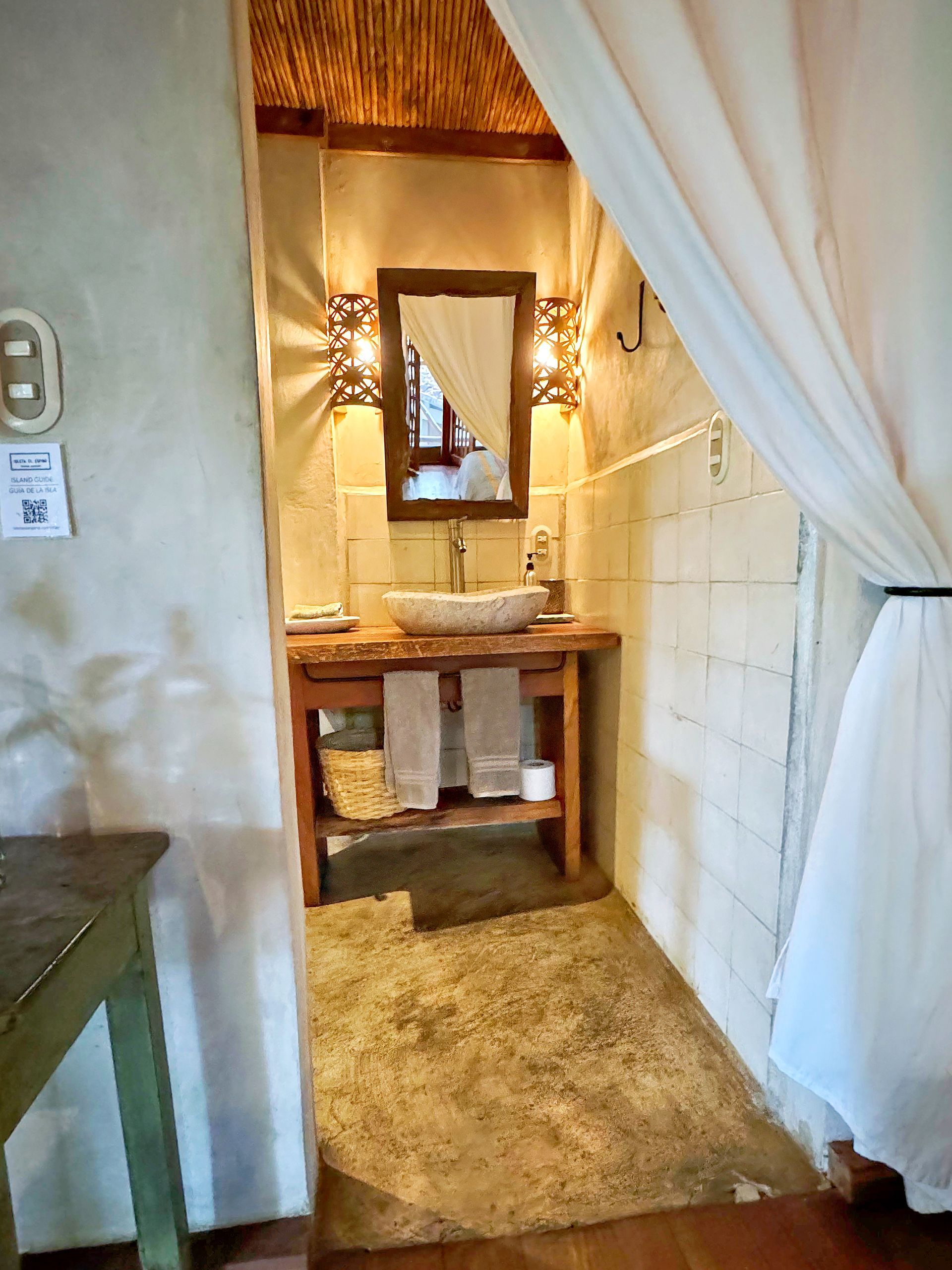 Bathroom with rustic sink, mirror, beige walls, and bamboo ceiling.