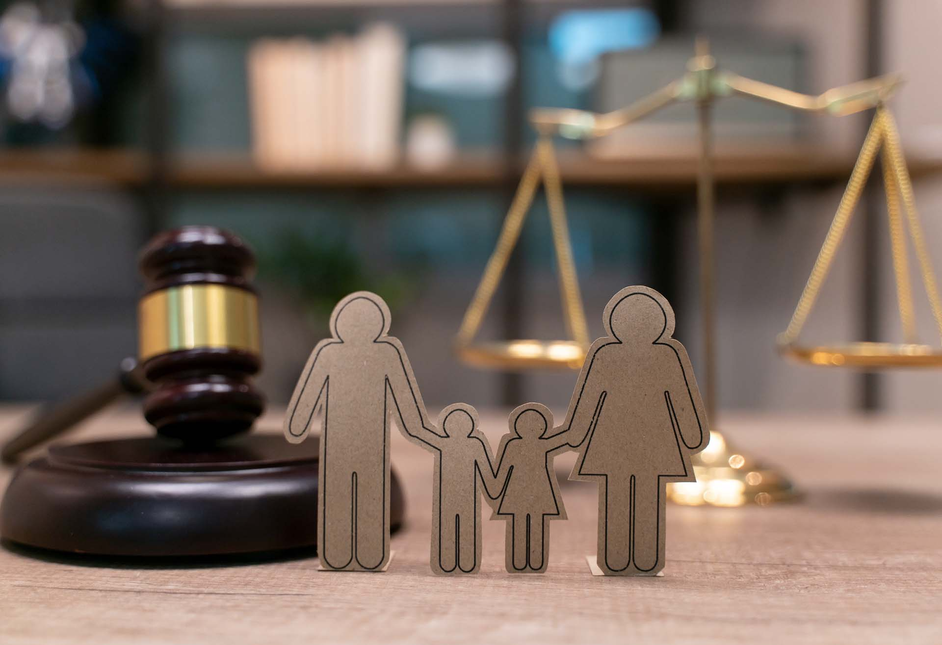 Family cutout in front of a gavel and scales of justice, symbolizing family law.