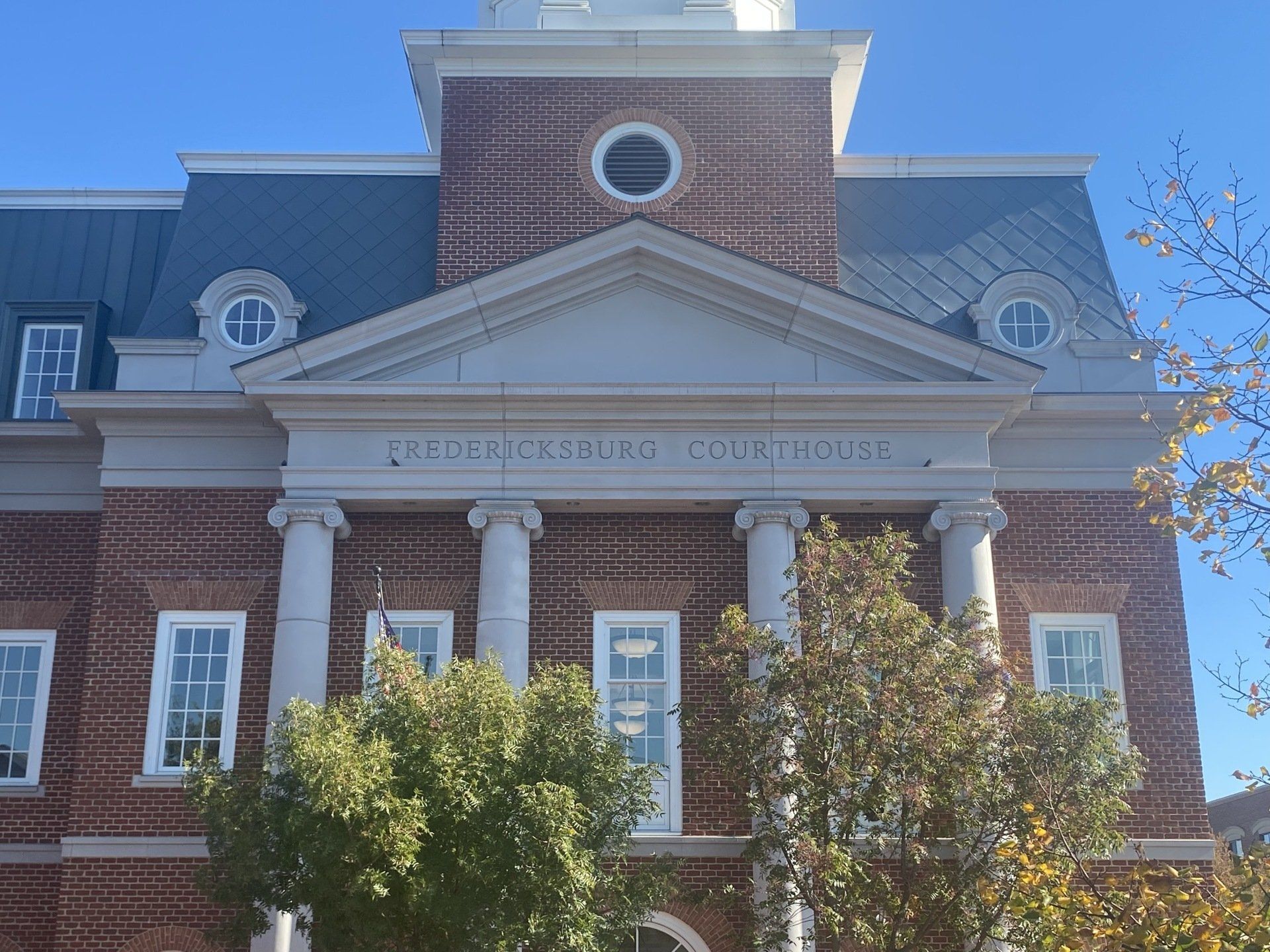 Fredericksburg Courthouse, brick building with white columns and dome, blue sky.