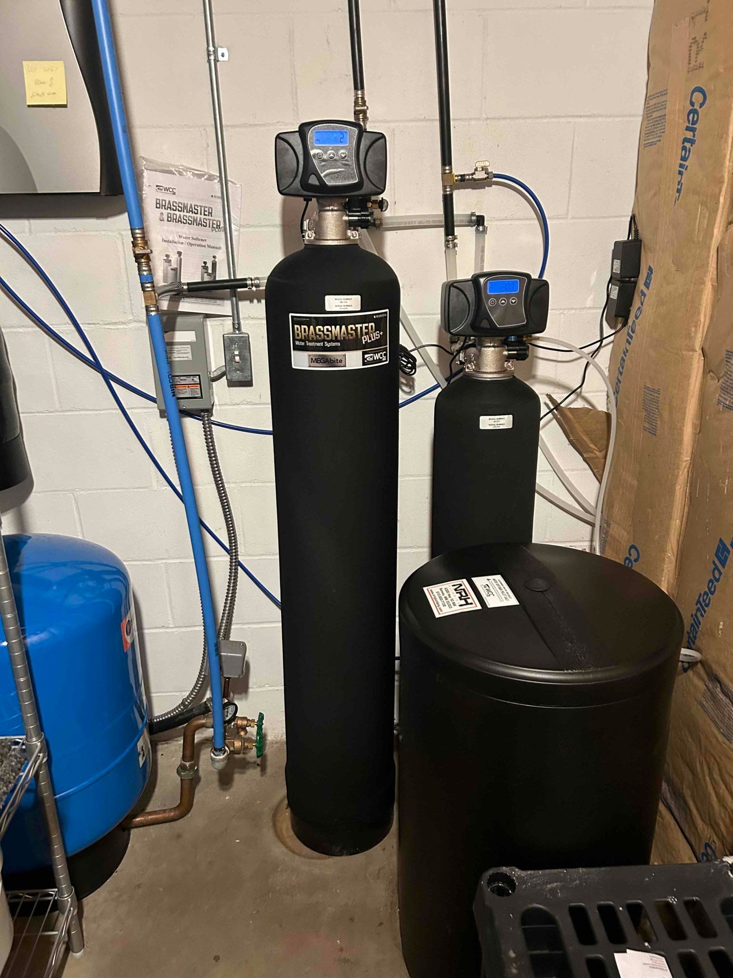 Water softener system in a basement setting with various tanks, filters, and copper pipes.