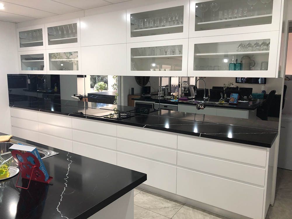 A Kitchen With White Cabinets and Black Counter Tops — Reflect Glass In Tuggerah, NSW