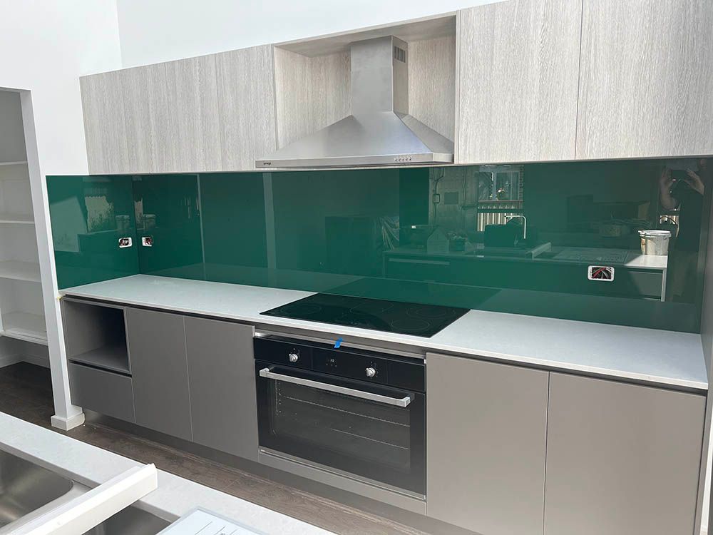 A Kitchen With a Green Glass Backsplash and a Stove Top Oven — Reflect Glass In Newcastle, NSW