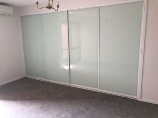 A Bedroom With Sliding Glass Doors and a Chandelier — Reflect Glass In Gosford, NSW