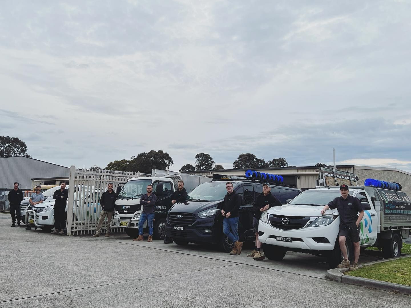 A Group of People Standing in Front of a Row of Trucks — Reflect Glass In Tuggerah, NSW